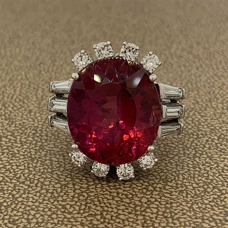 A remarkable ring featuring an 18.57 carat rubellite tourmaline. The red oval cut gem is ornamented by 1.70 carats of colorless diamonds. The top and bottom of the ring are decorated with round and baguette cut diamonds decorate the two sides of