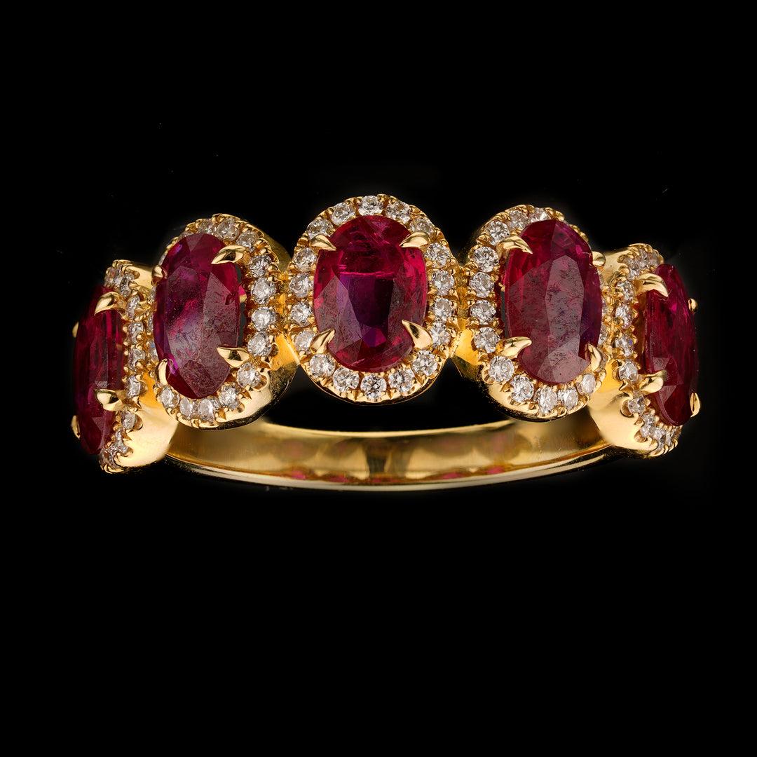 This 18 karat yellow gold half eternity band features five oval-cut rubies totaling 1.86 carats with incredible deep red color and great clarity each surrounded by a single halo of round white diamonds for contrasting sparkle totaling 0.31 carats of