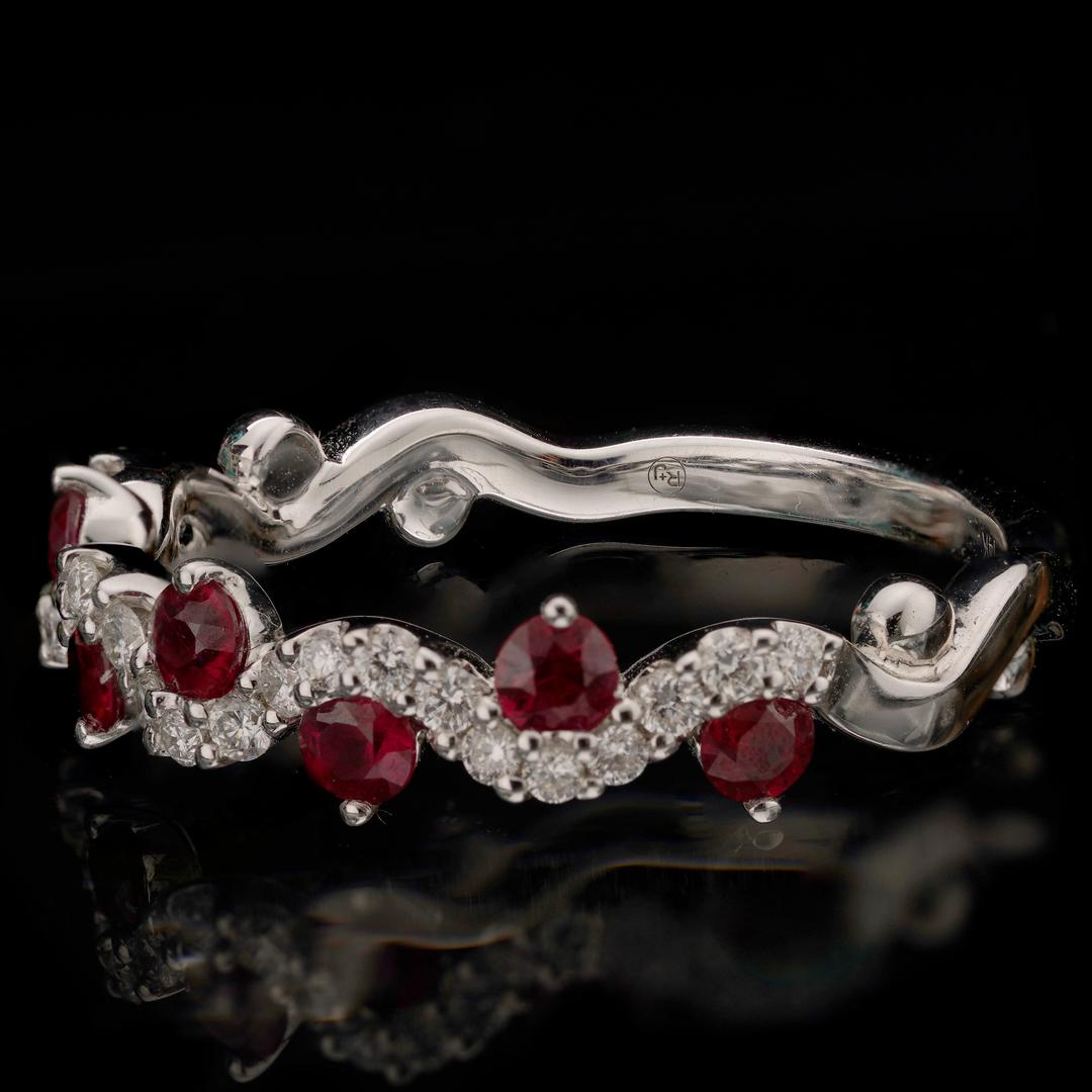 This dynamic and fiery ring features an undulating line of twenty-three sparkling round white diamonds totaling 0.20 carats punctuated above and below by seven contrastingly rich red, beautifully translucent rubies totaling 0.50 carats – all set in