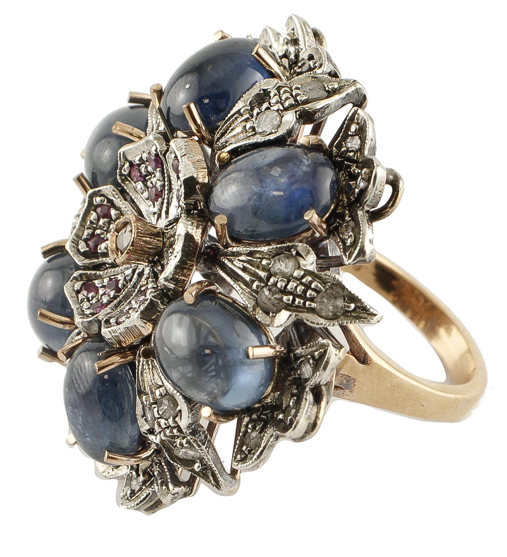 Beautiful retro ring in 9k white gold and silver. This ring is designed with a central flower studded with rubies petals and a central diamond. The flower is surrounded by 6 blue sapphires and flowery details in gold and silver studded with