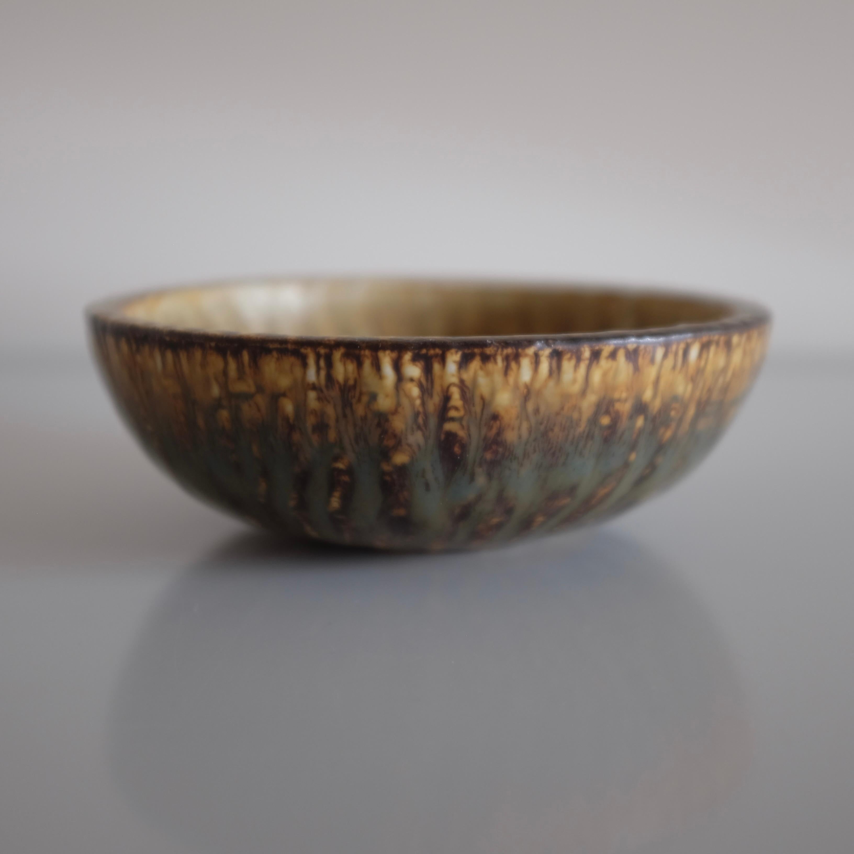 Small ceramic bowl from the Rubus collection by Gunnar Nylund for Rörstrand, Sweden. Decorative flame like design in brown, black and beige colors with designers signature underneath. In a good vintage condition. 
Dimensions: D 6.75 in. x H 2.25 in
