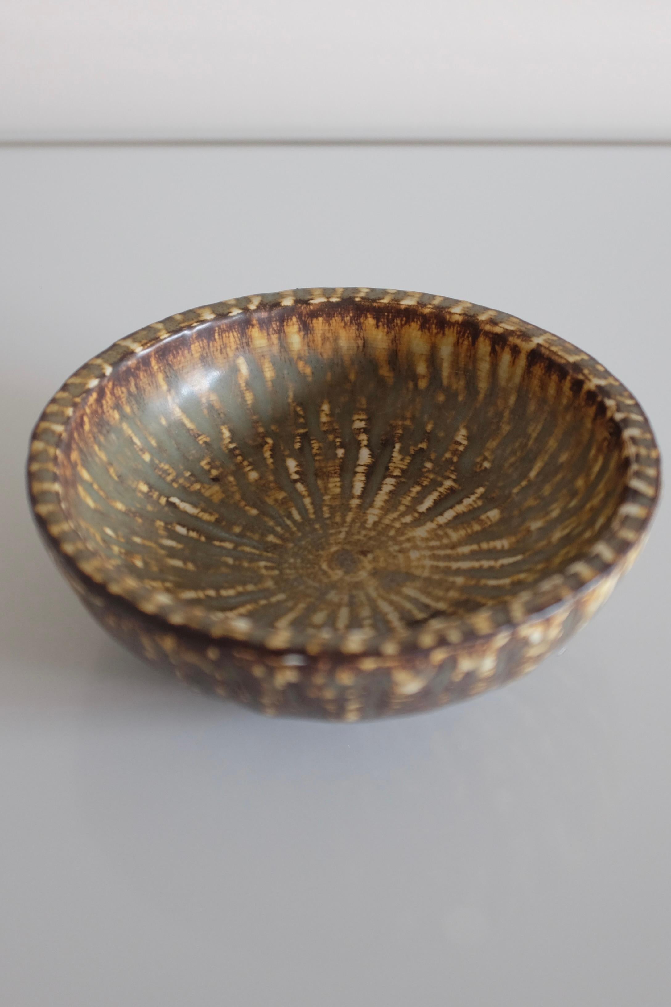 Cuenco pequeño de cerámica de la colección Rubus de Gunnar Nylund para Rörstrand, Suecia. Diseño decorativo en forma de llama en colores marrón, negro y beige con la firma del diseñador debajo. En buen estado vintage.

Dimensiones: P 6,75 pulg x A