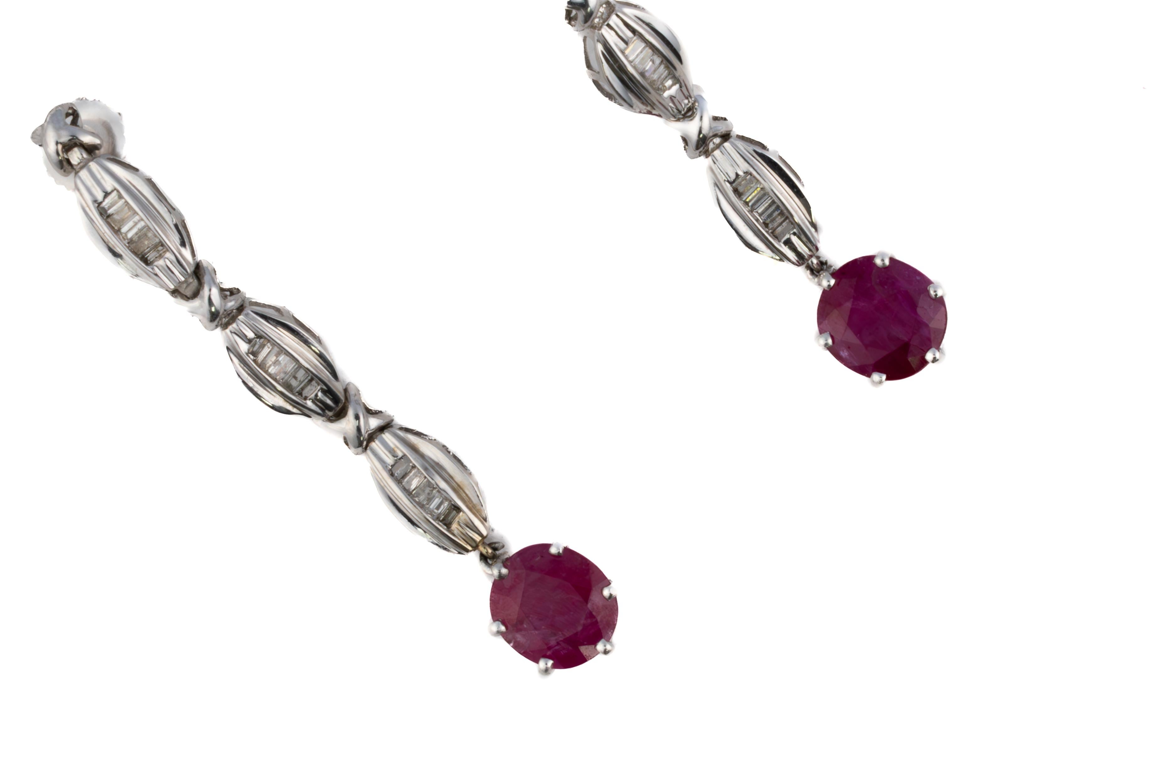 Ruby and Baguette Diamond Drop Earrings

Description:
These elegant earrings feature vivid round rubies suspended from a refined line of vertically-set baguette diamonds. Each link is crafted in white gold with a softly ribbed surface, forming a