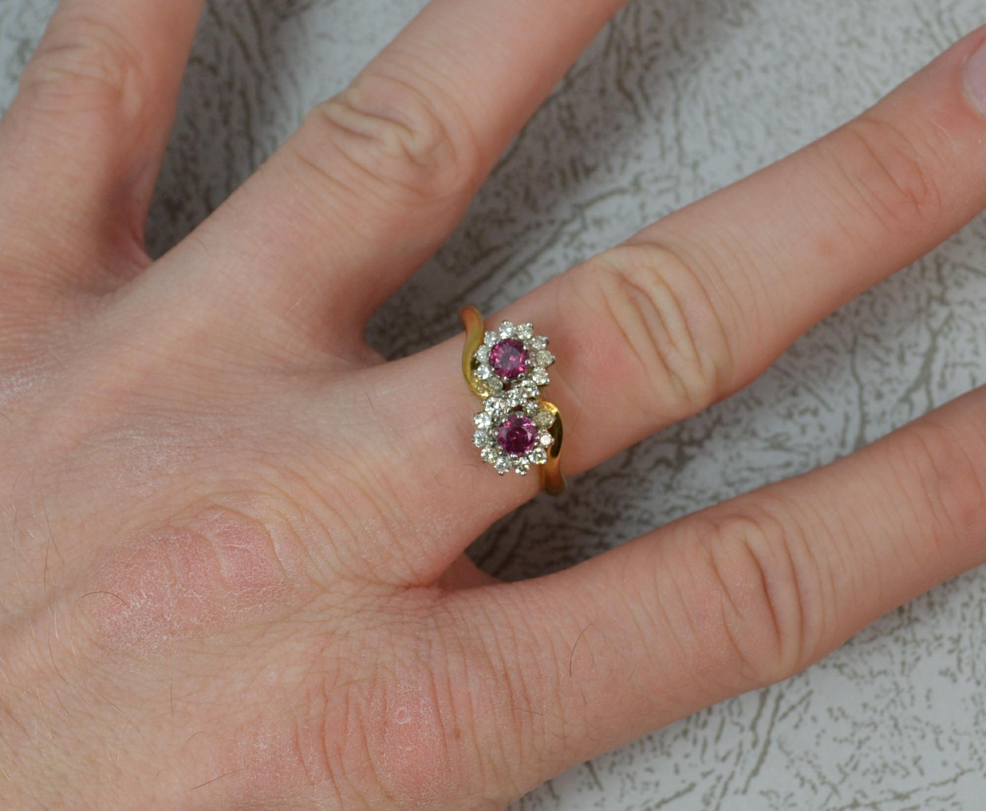 A superb Ruby and Diamond cluster ring in 18ct Gold.

Designed with two round cut pink red natural ruby stones, 3.6mm diameter.

Each surrounded by multiple round cut natural diamonds.

14mm spread of stones, protruding 6.5mm off the finger.

18