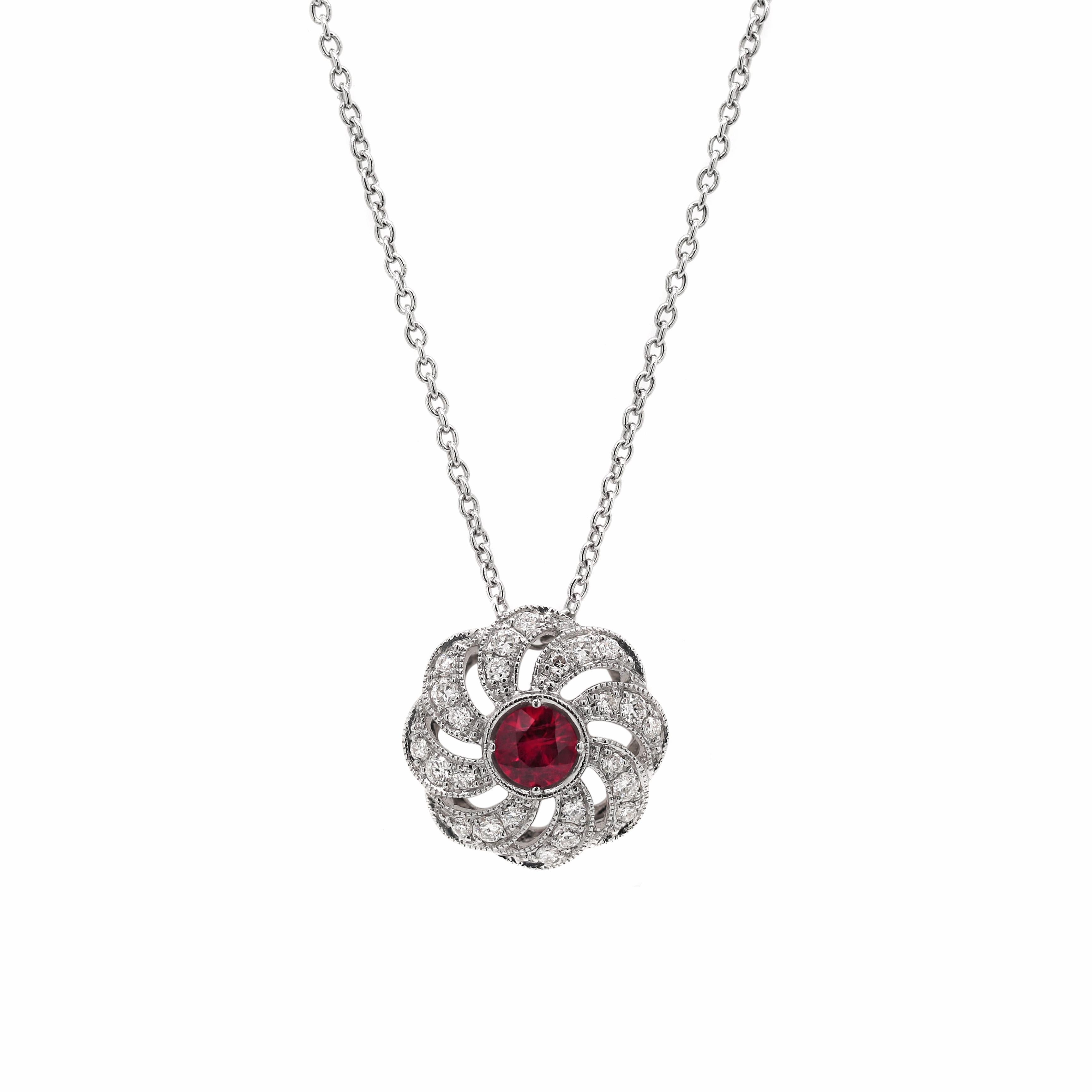 This exquisite 18 carat white gold set features a floral designed ruby and diamond pendant and matching earrings. The pendant is beautifully set with a vibrant 0.25ct ruby in the centre, surrounded by 24 fine round brilliant cut diamonds, weighing