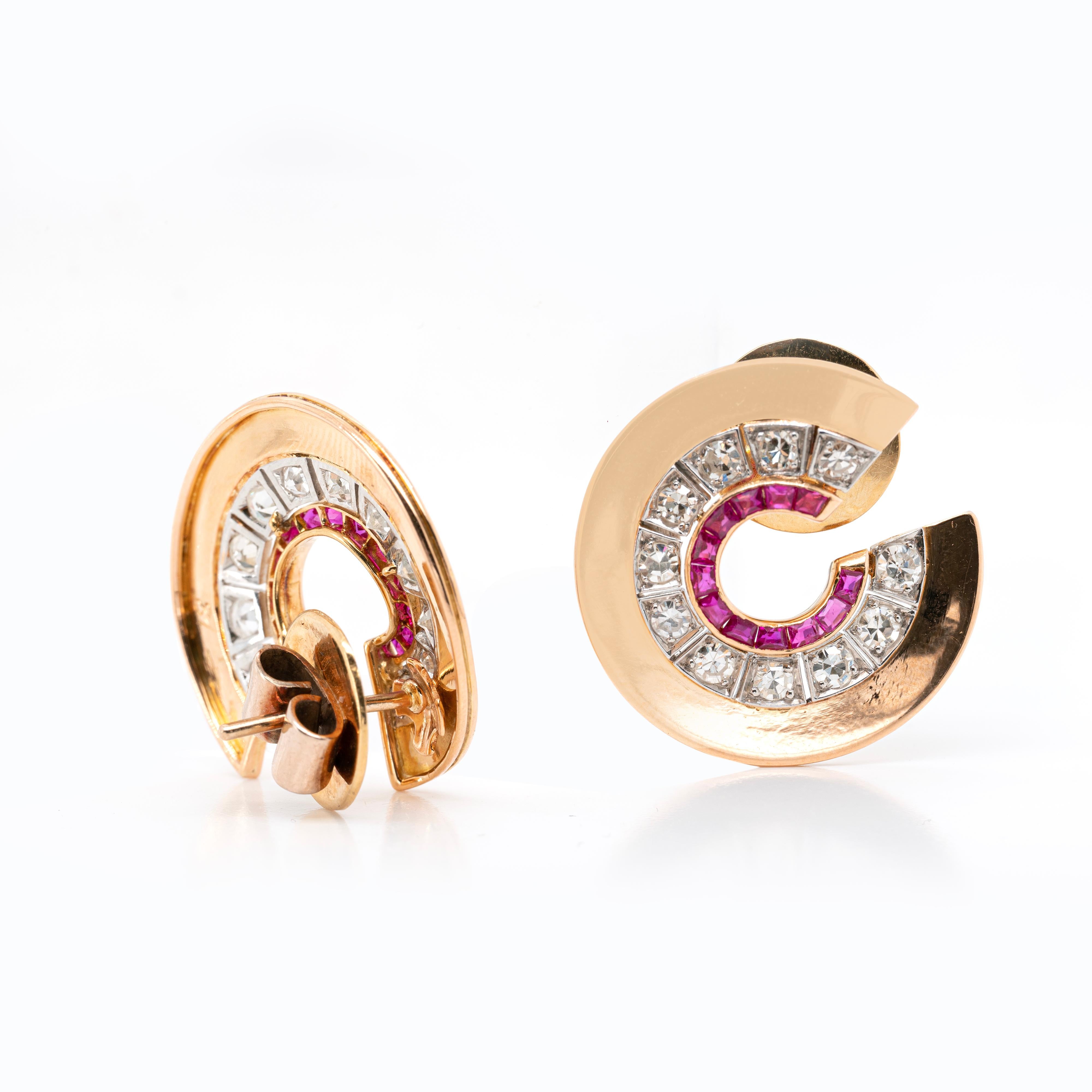 These gorgeous Art Deco inspired stud earrings are masterfully designed as a swirl which beautifully curves around the ear like a half hoop. The inner edge of the earrings is embellished by a row of 12 channel set vibrant rubies weighing