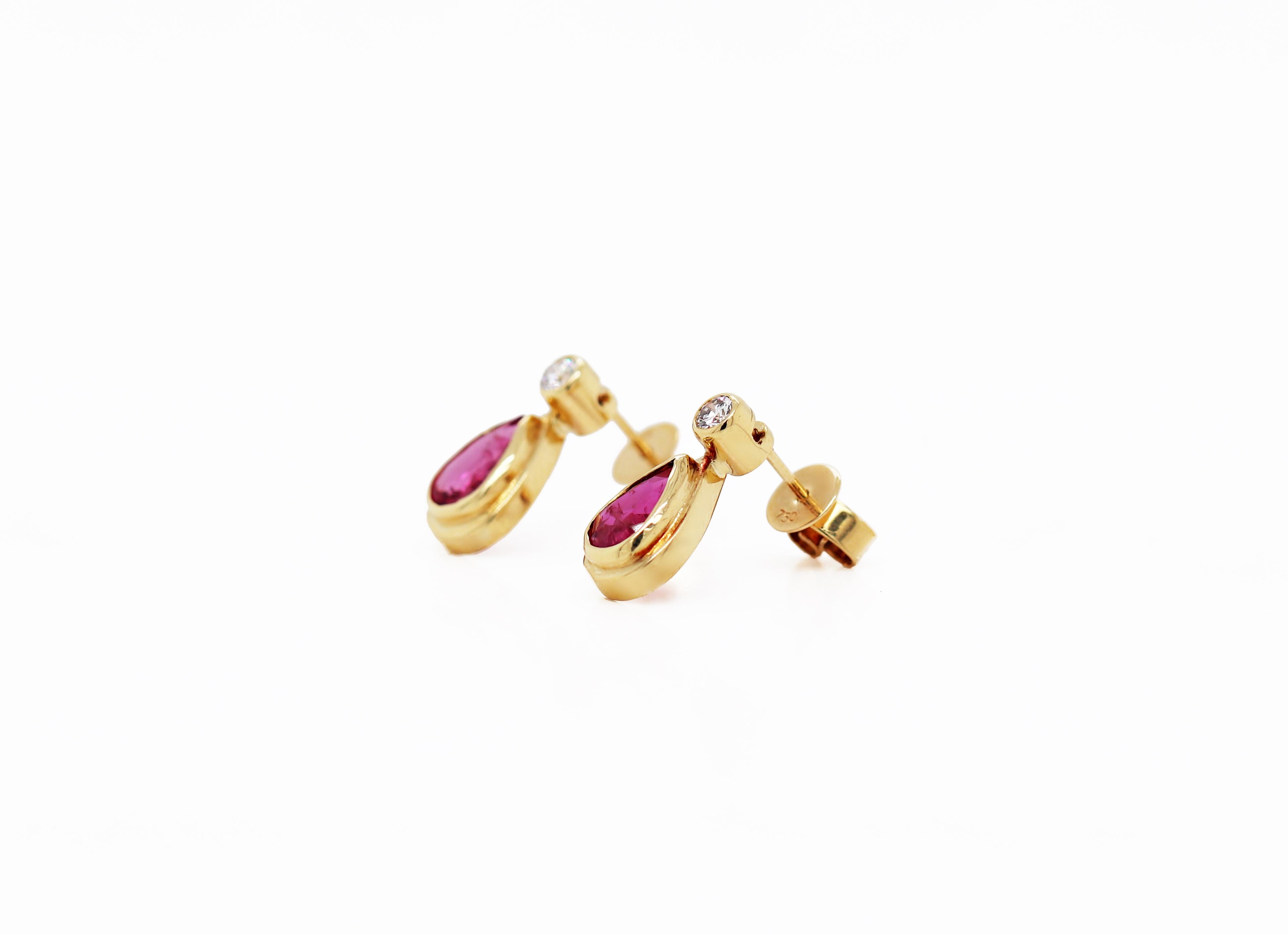 These beautiful earrings feature a vibrant pear shaped ruby weighing approximately 1.05ct each, mounted in a rub over, open back setting. The ruby is wonderfully accompanied by a fine quality round brilliant cut diamond above it, weighing