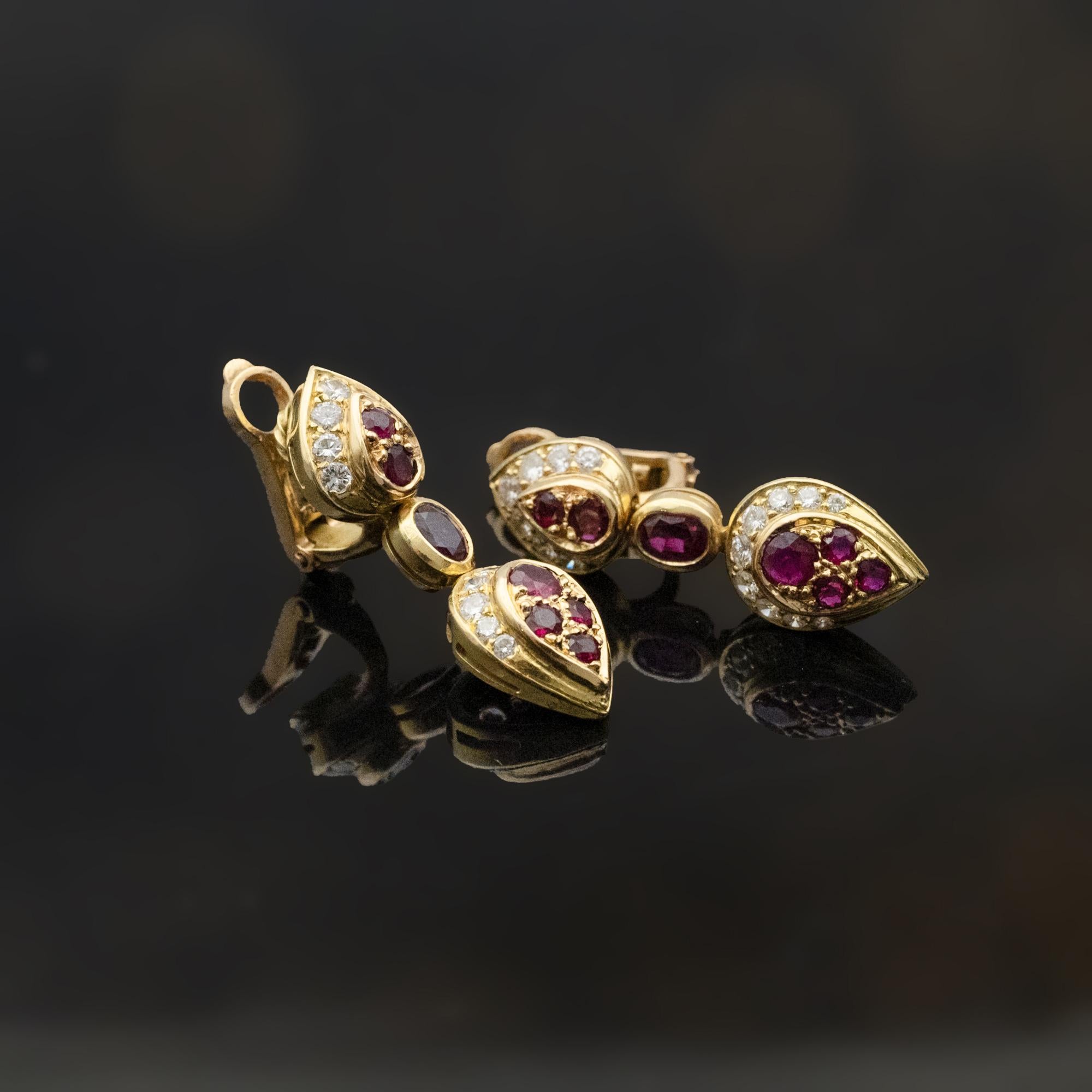 Un paio di orecchini articolati, offerti da Claris.A, realizzati in oro giallo 18 carati, disegnati con tre elementi collegati che formano una composizione verticale equilibrata. Ogni sezione è incastonata con rubini e diamanti bianchi disposti