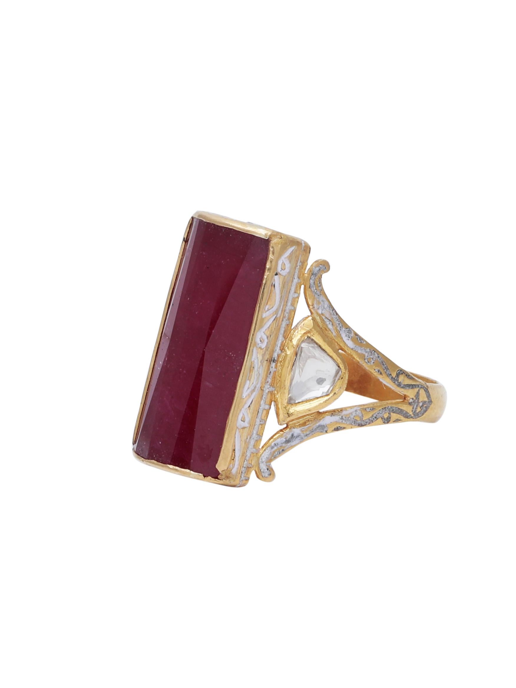 A stunning ring with Ruby and 2 uncut diamonds on the side with white enamel detailing. All handcrafted in 18K Gold.
The beautiful red Ruby in the centre of the cocktail ring is of 12 carats. Its of an unusaul Rectangle shape and with facets on the