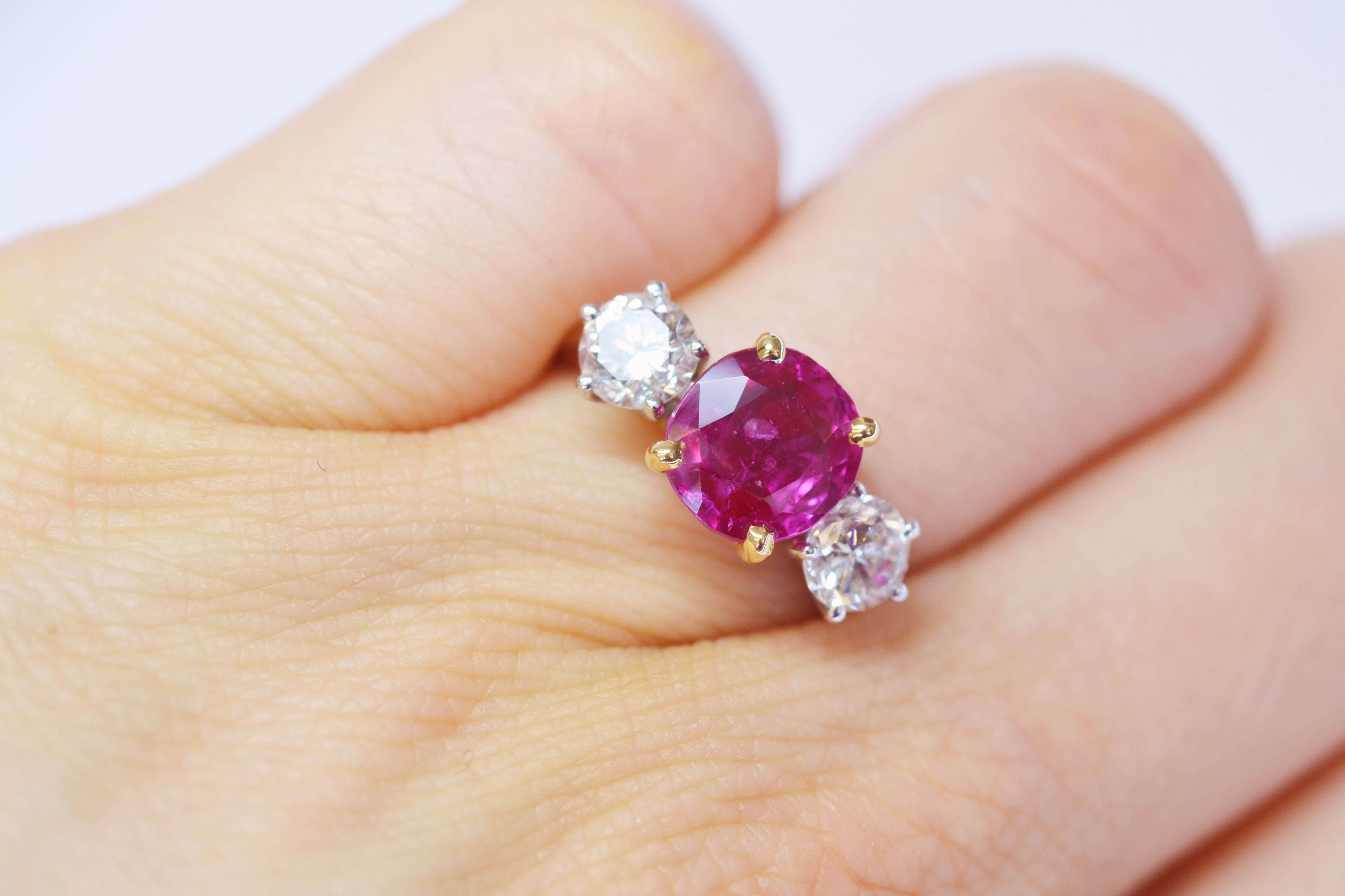 Handcrafted ring in 18k yellow gold with a vibrant 2.50 carat pinkish ruby between two glittering diamonds. This ring has an open basket setting which lets the light come through from every angle, illuminating the beauty of the three stones. 

Ring