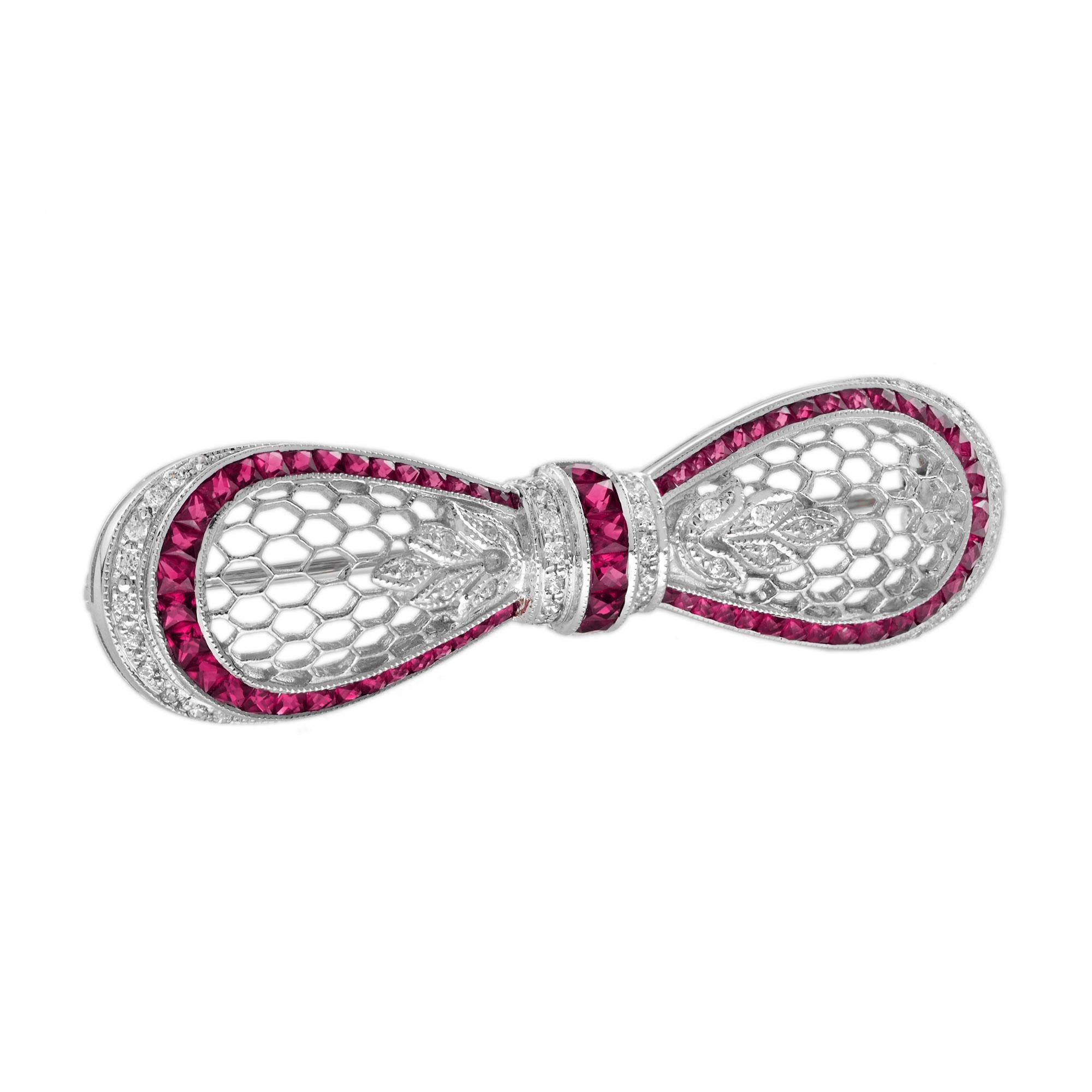 A truly beautiful white gold bow brooch set with diamonds and French cut rubies. The milgraining of the metal edges allow the diamonds and gemstones to sparkle without competing with the reflected light from a highly polished white gold edge.