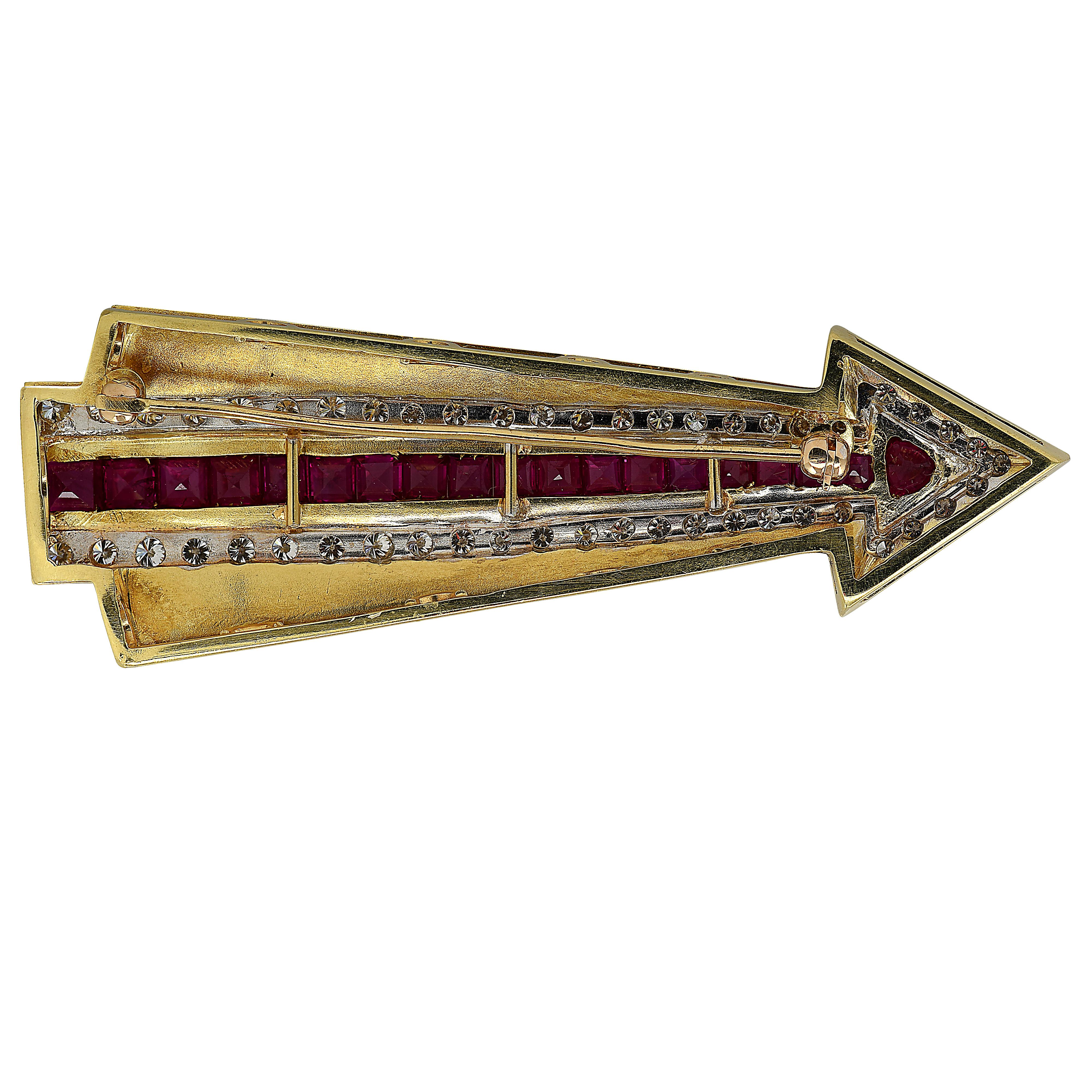 Striking arrow brooch pin crafted in 18 karat yellow and white gold, featuring 19 square cut rubies weighing approximately 2.15 carats total, and 49 round brilliant cut diamonds weighing approximately 2.2 carats total, G color, VS clarity. This