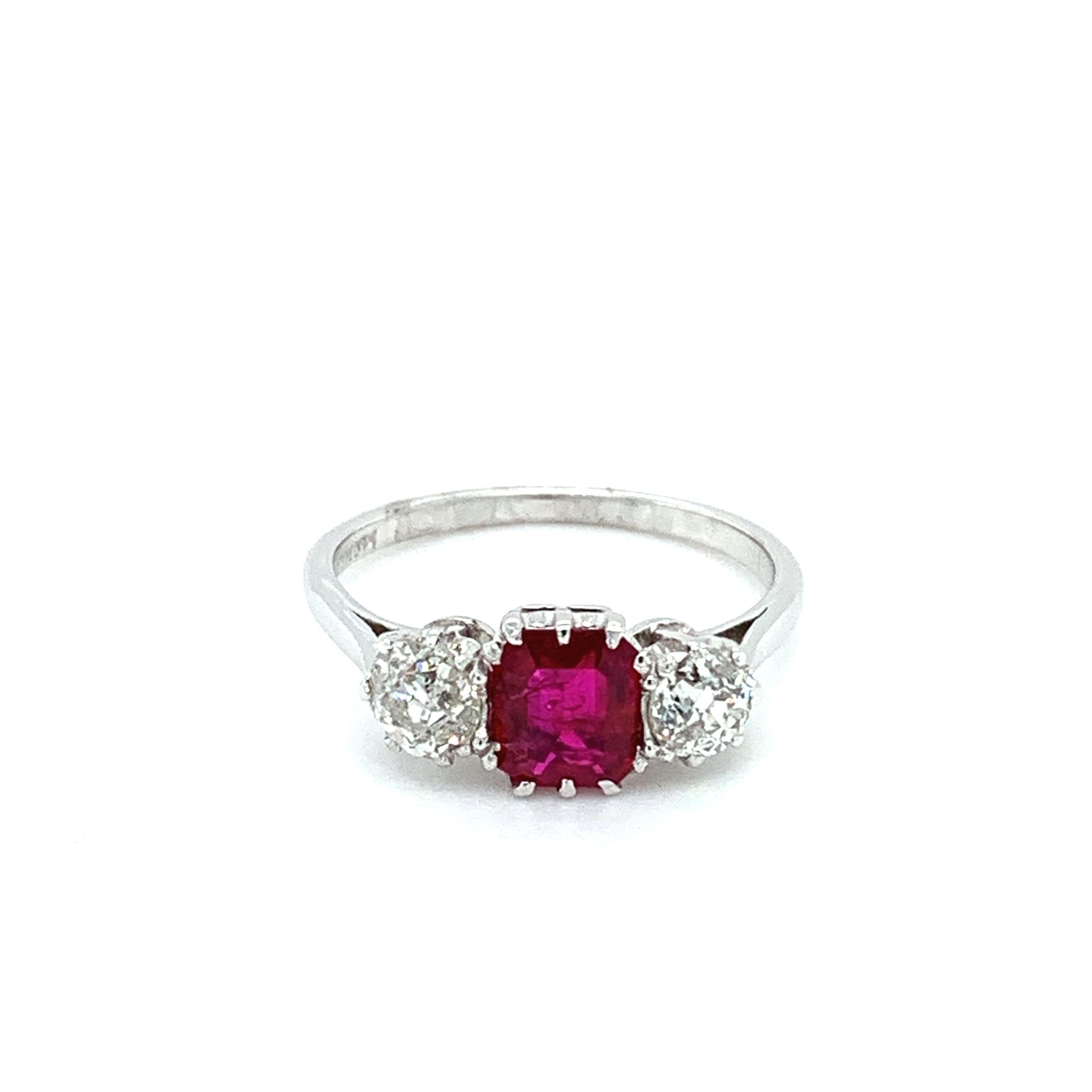 This stunning engagement ring from Trilogy features a beautiful 1.54ct ruby, set in platinum. The ring is adorned with three diamonds, two of which are rubies, giving it a unique and elegant look. The ruby is a natural creation, with an excellent