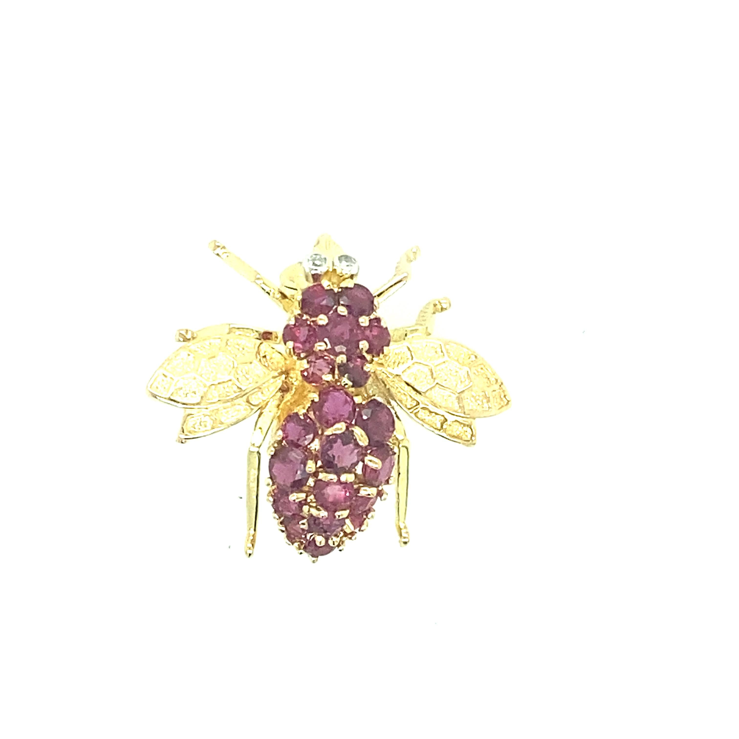 One 14 karat yellow (stamped 14K) gold bee pin set with twenty round rubies and two full cut diamonds, approximately 0.03 carat total weight with matching I/J color and SI clarity.  The pin measures 1 inch long and is complete with a traditional pin