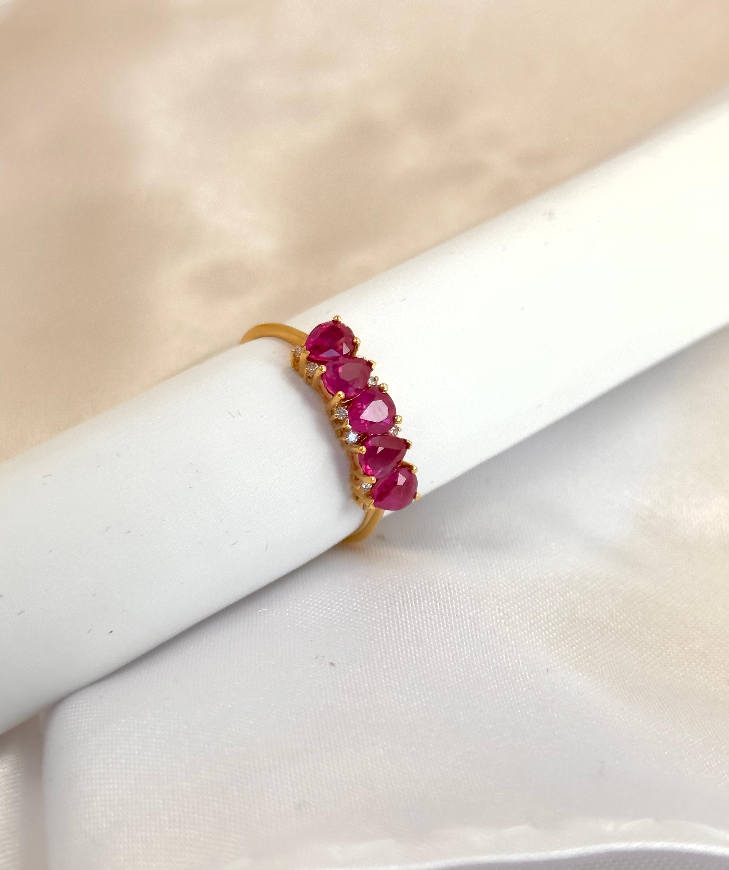 Pear shape rubies lined up next to each other in this half band ring with small diamonds! The pear shape rubies are in a forward and reverse pattern set in a basket setting ring. The smaller diamonds have their own personal basket setting in between