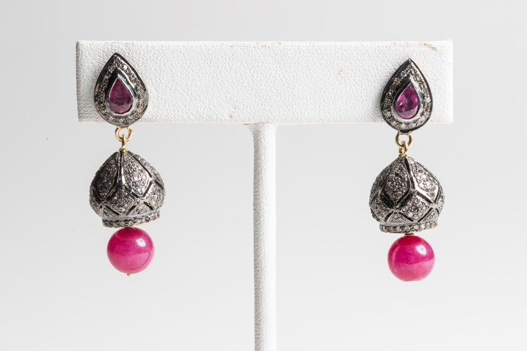 A pair of pave`-set, round-cut diamonds set in sterling silver with a faceted, pear-shaped ruby on the post also surrounded by diamonds and a Burmese ruby bead dangling from the bottom. 18K gold post for pierced ears.  Diamonds total 2.38 carats and