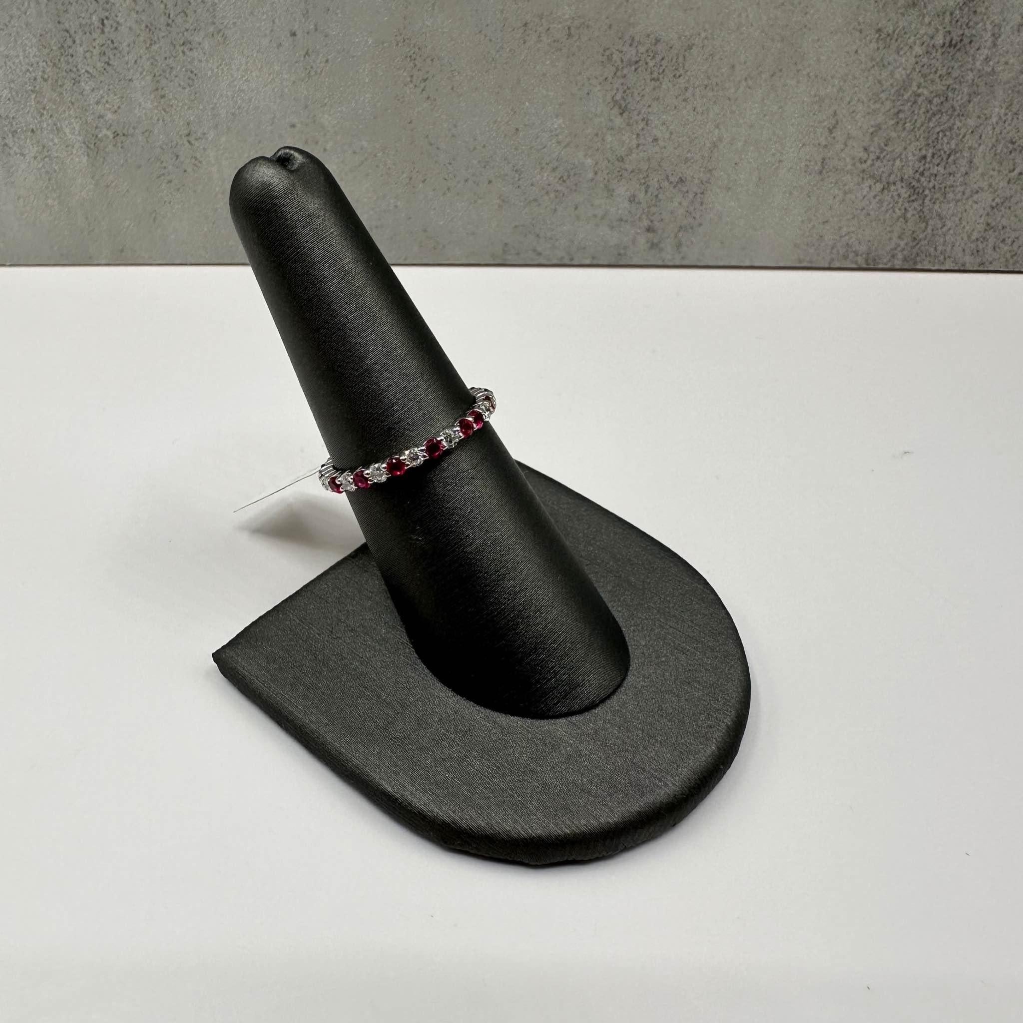 This stunning Ruby and Diamond Eternity Ring in 18kt white gold features 0.53ctw of natural GH SI round diamonds and 0.72ctw of vibrant round rubies, alternating for a timeless, elegant design. At one point, two rubies are set next to each other,