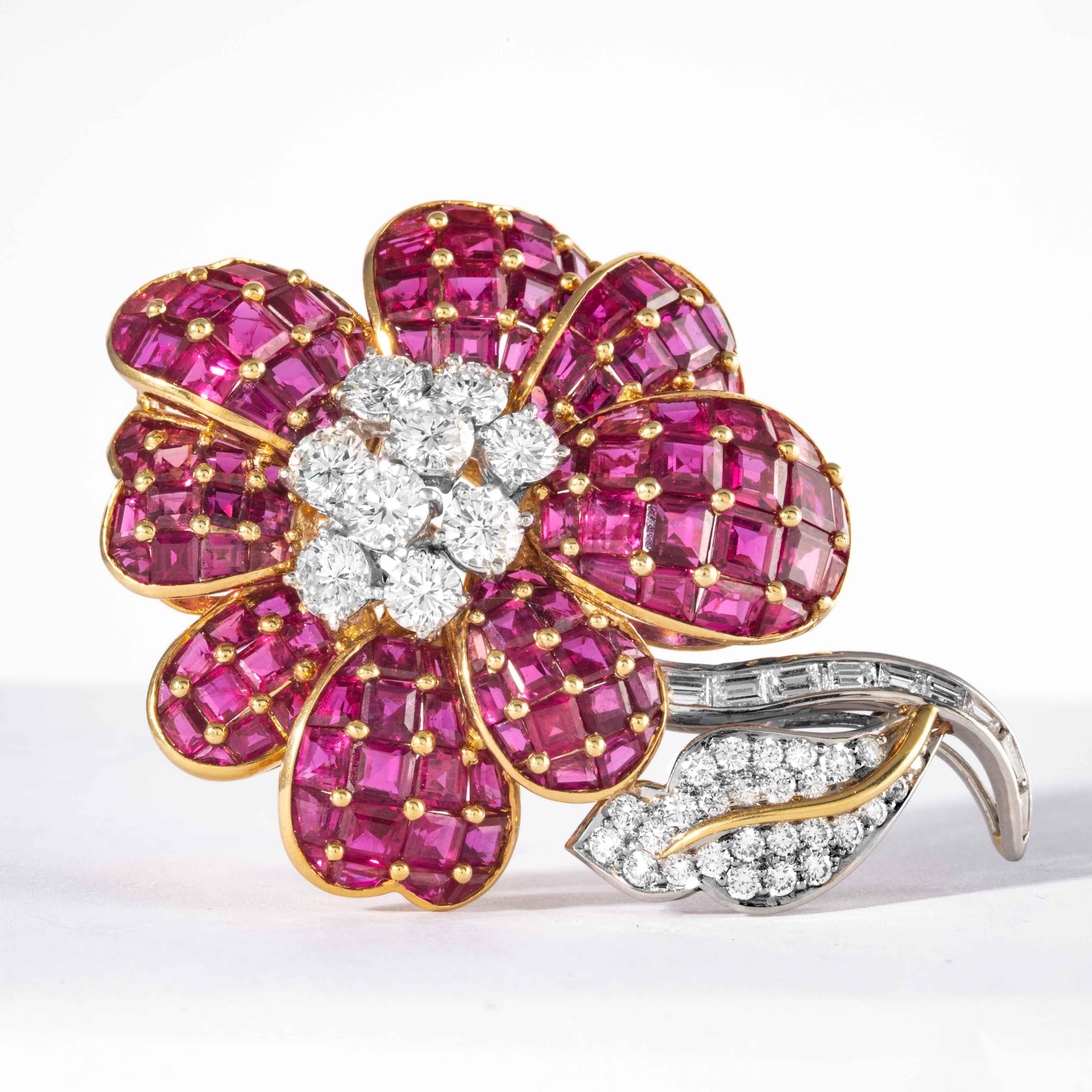 This whimsical floral motif brooch is comprised of 18 karat yellow and white gold and consists of step-cut rubies having an estimated total weight of 13 carats, 7 round brilliant diamonds in a blossoming flower design with baguette and round