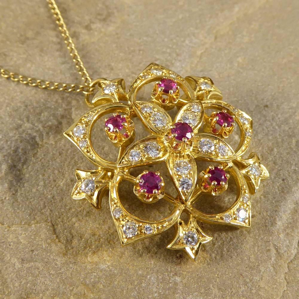 This is a beautiful Vintage 18ct yellow gold pendant is suspended on a 18ct yellow gold chain. It has a flower in the centre set with Diamonds on the petals and a Ruby in the middle. The outer flower is also set with Diamonds and there are Rubies