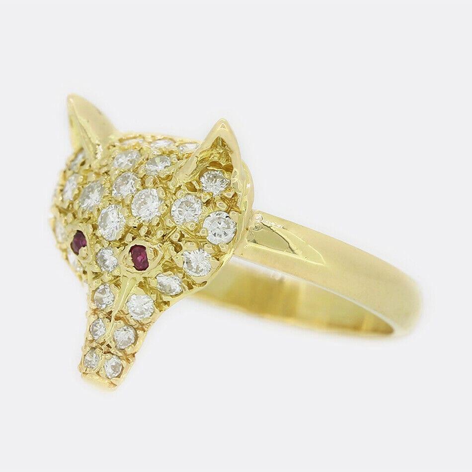 This is an 18ct yellow gold fox head ring. The fox head features an array of brilliant round cut diamonds and rubies playing the part of the foxes eyes and has a plain 18ct yellow gold band. The ring started life as a stick pin but has been
