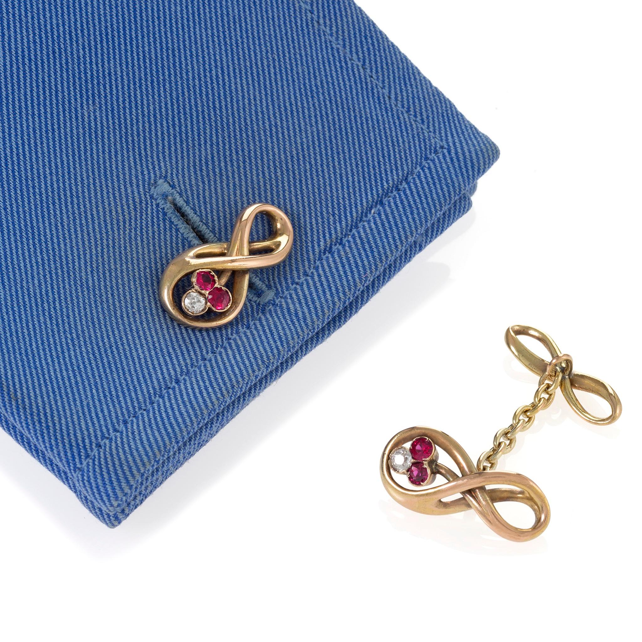 These Art Nouveau double cuff links by a Russian jeweler are designed as stylized infinity links set with diamond and ruby mêlée, joined by a line of trace link chain to smaller infinity links. Designed by a free and exuberant hand, these unusual