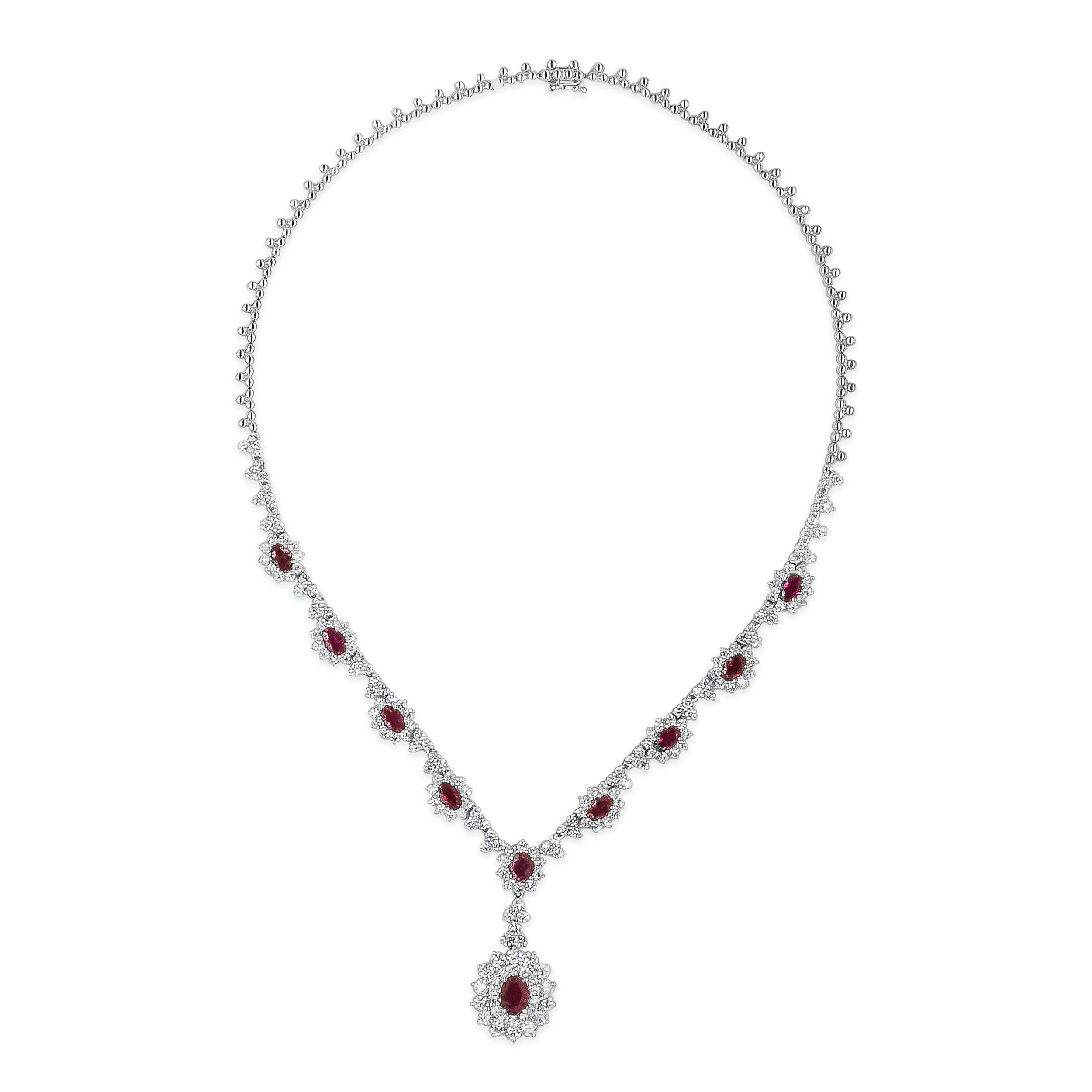 Ce collier élégant et de grande classe présente un pendentif en forme de goutte avec un rubis ovale de 1,30 carats, entouré de deux rangées de diamants ronds de taille brillant. Suspendue à une chaîne en forme de halo sertie de rubis et de diamants