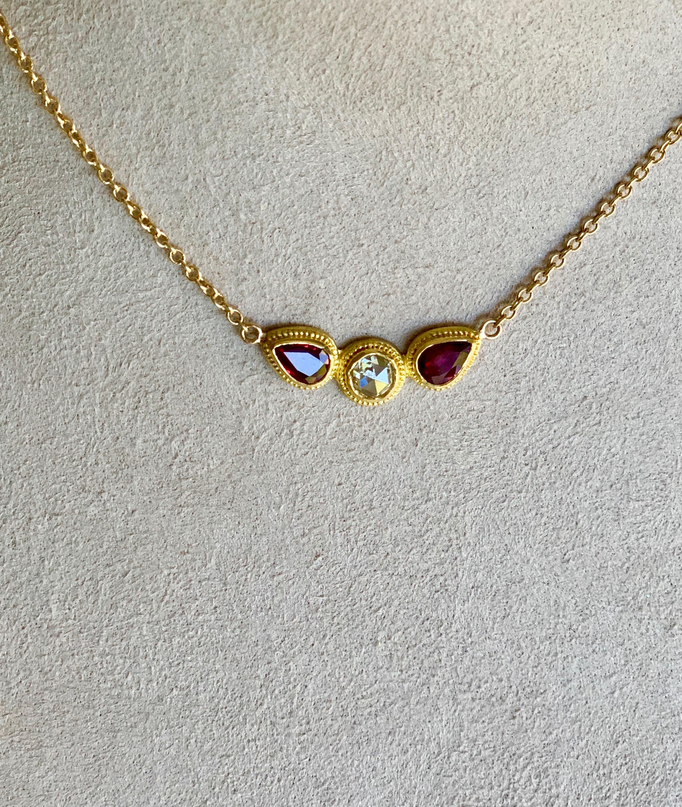 This winged pendant necklace with rose cut Diamond and pear shape Rubies, is set in 22 Karat gold with granulation.
The delicate chain is 18Karat yellow gold with a lobster claw closure allowing to shorten the chain by 1 inch if desired.
Diamond is