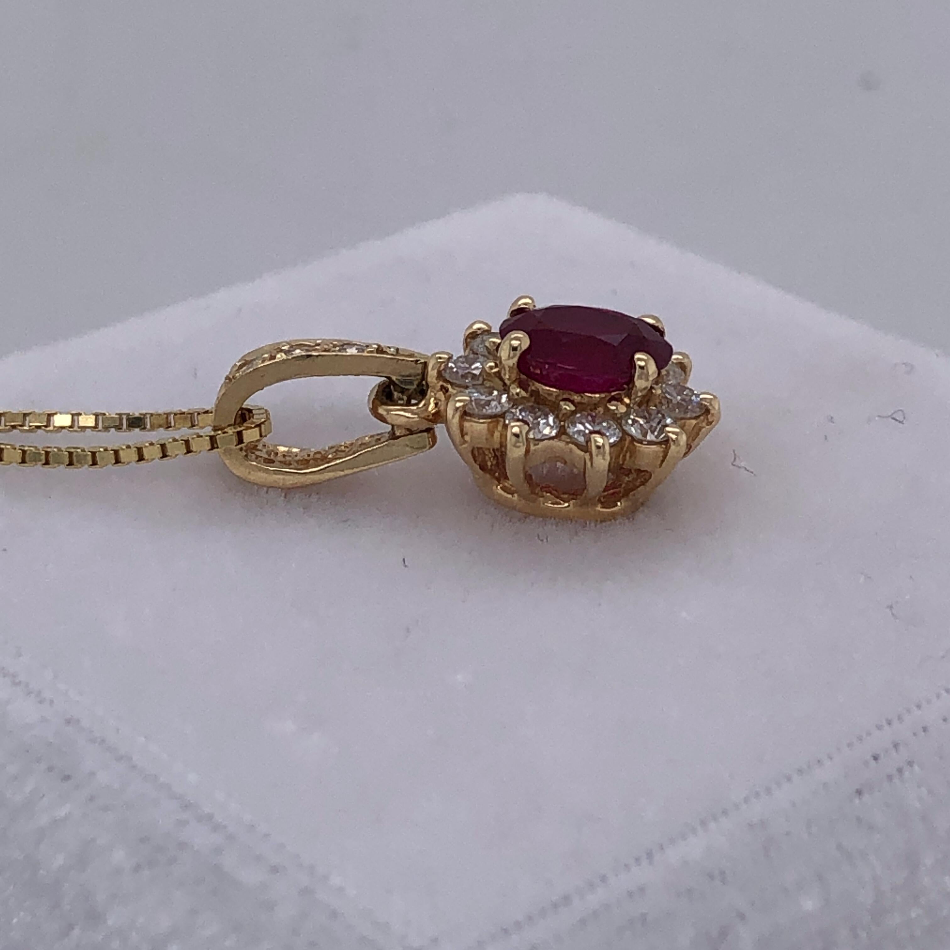 One 14 karat yellow gold oval shaped pendant, prong set with one 6.8 x 5.2mm oval ruby approximately 1.03 carat total, surrounded by ten 1.8mm prong set round brilliant diamonds, approximately 0.50 carat total weight with matching H/I color and