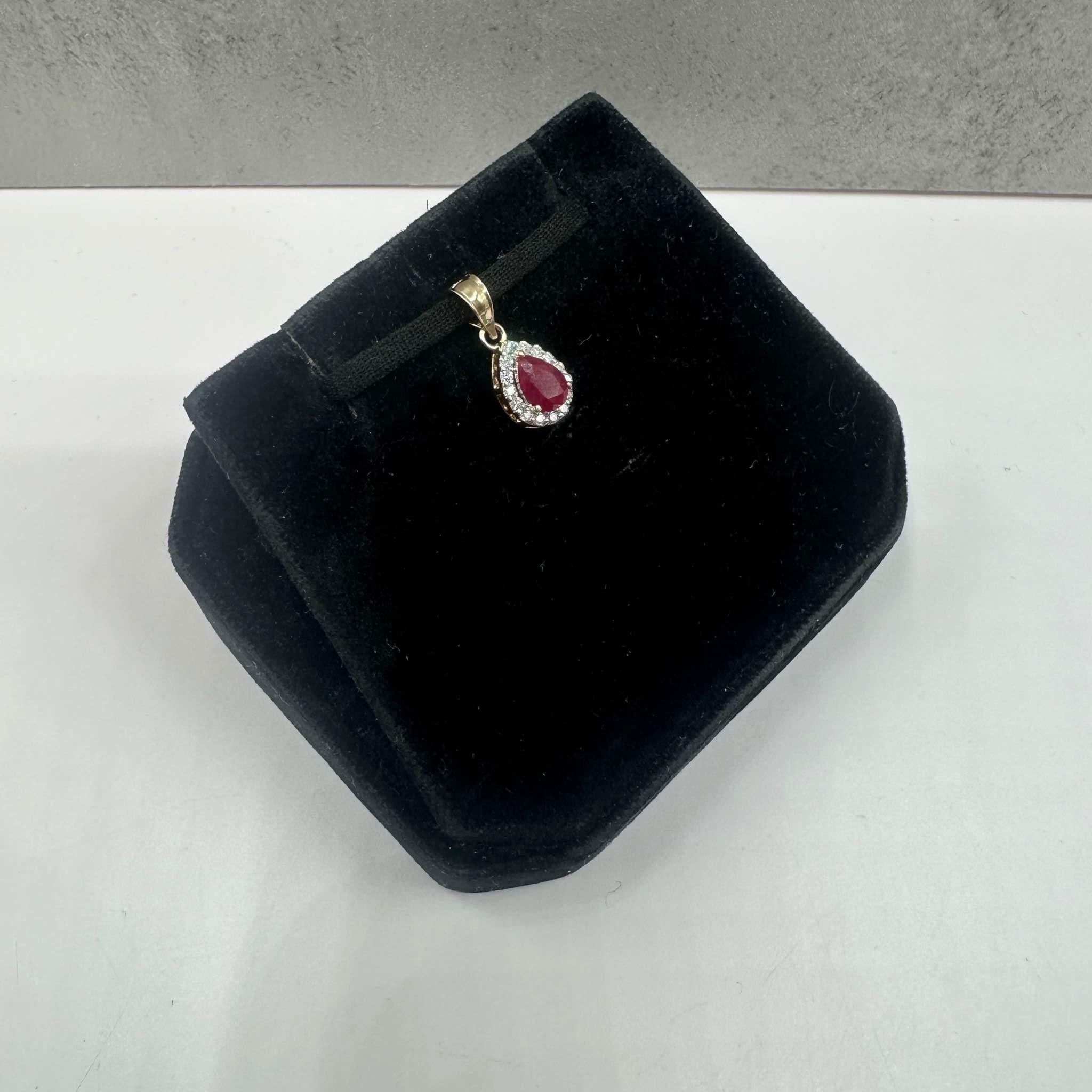 Dieser wunderschöne Rubin- und Diamantanhänger aus 14-karätigem Gelbgold besteht aus einem 5,7 x 4,1 mm großen Rubin im Birnenschliff, der durch 0,08 ct runde natürliche HI I1-Diamanten ergänzt wird, die für zusätzlichen Glanz sorgen. Mit einem