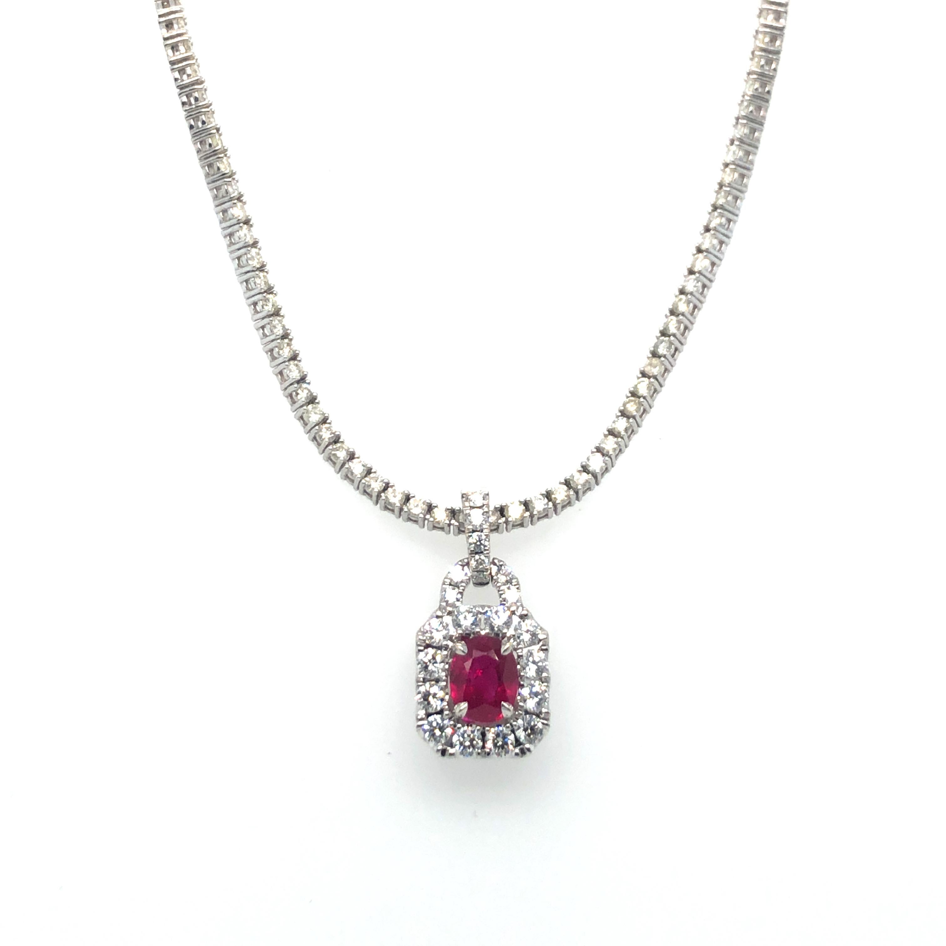 Ruby and Diamond Pendant Riviera Necklace in 18K White Gold. The pendant features an oval cut ruby that is approximately 1 carat,  accented by a halo of brilliant cut round diamonds. Then necklace is 18