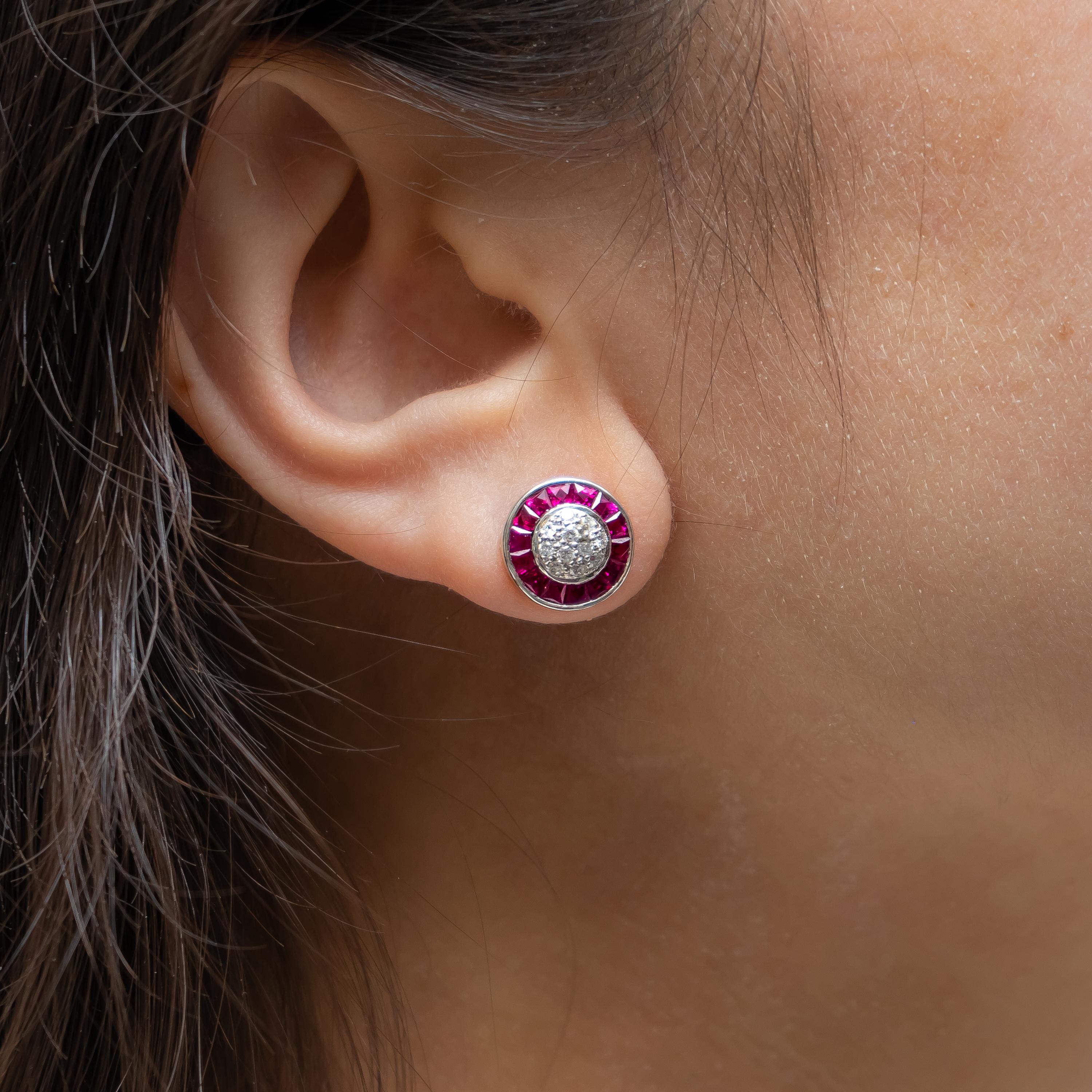 A pair of ruby and diamond cluster earrings, with a pavé set diamond centre, and a French-cut ruby surround. Mounted in platinum. Estimated total diamond weight 0.31ct, estimated total ruby weight 1.89ct.