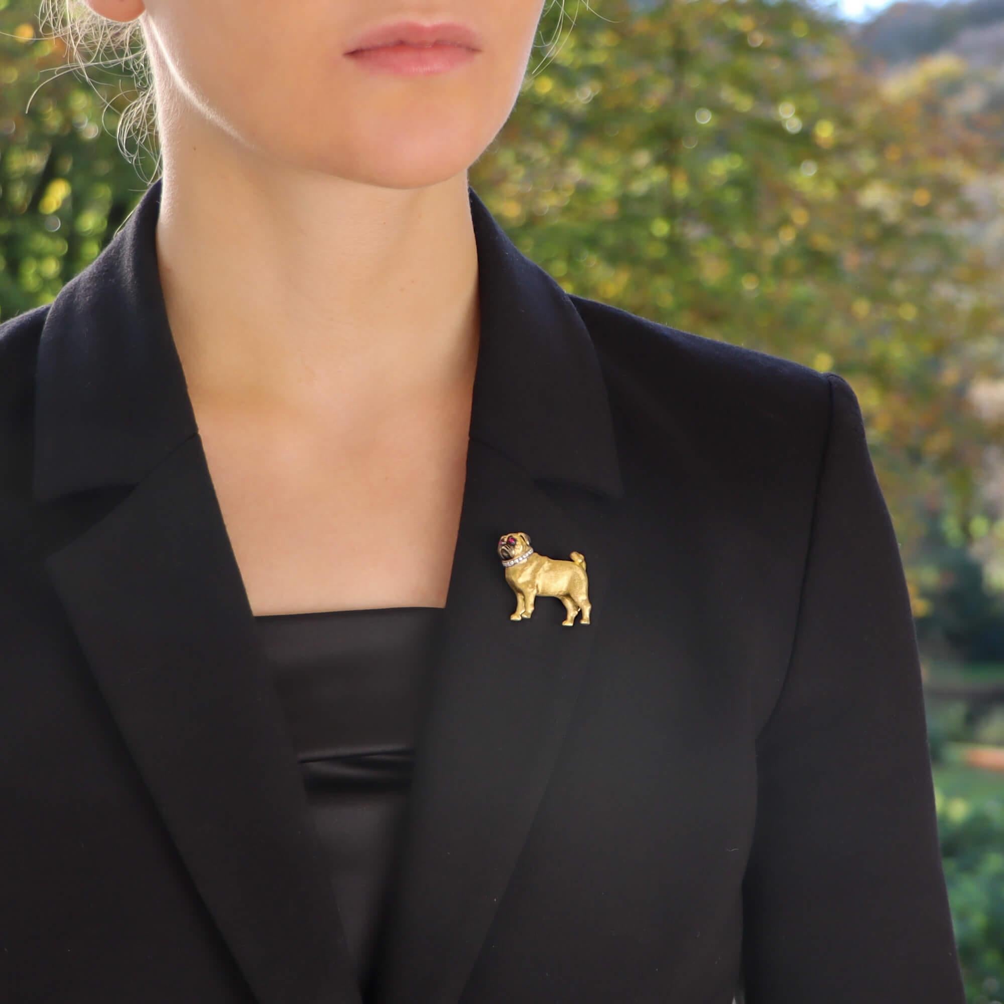 A beautiful ruby eyed Pug dog brooch set in 18k yellow gold.

The brooch depicts a standing Pug; which is set with two vibrant round cabochon ruby eyes. The Pug’s body has been handcrafted and beautifully detailed with brushed, engraved and rhodium