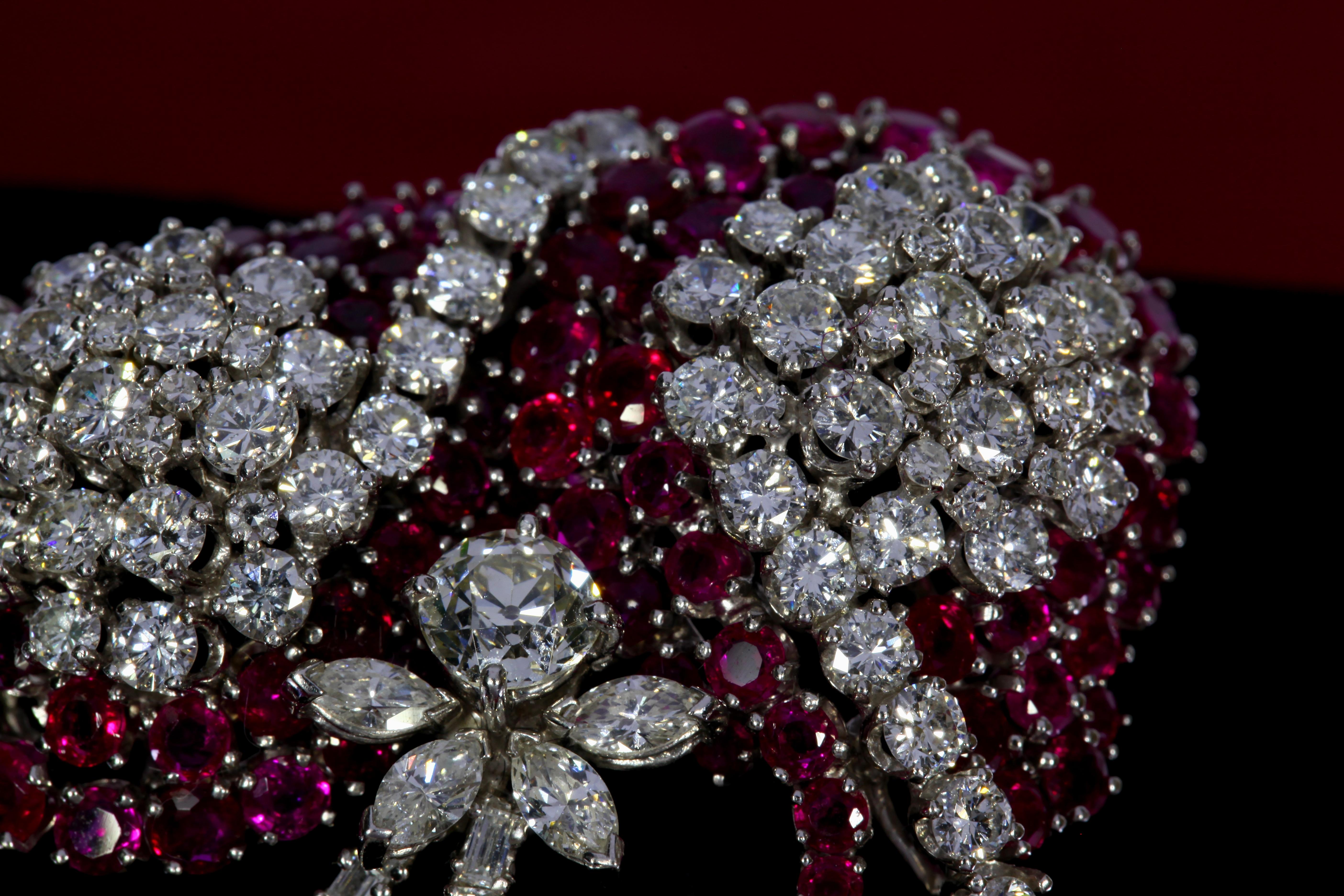 The brooch of stylized ribbon design is set with round rubies and diamonds. It is accented by old European-, marquise-, and baguette- shaped diamonds. The rubies weigh combined approximately 11.20 carats and the diamonds weigh combined approximately