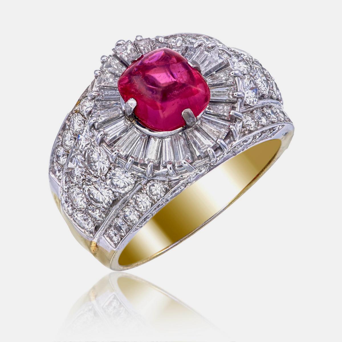 Bei diesem Ring von REWA Jewels steht ein 2,87-karätiger Cabochon-Rubin im Mittelpunkt. Er ist umgeben von einem Halo aus Diamanten, darunter Brillanten und Baguettes, mit einem Gesamtgewicht von 4,57 Karat.

Der Ring ist aus 18 Karat Gold