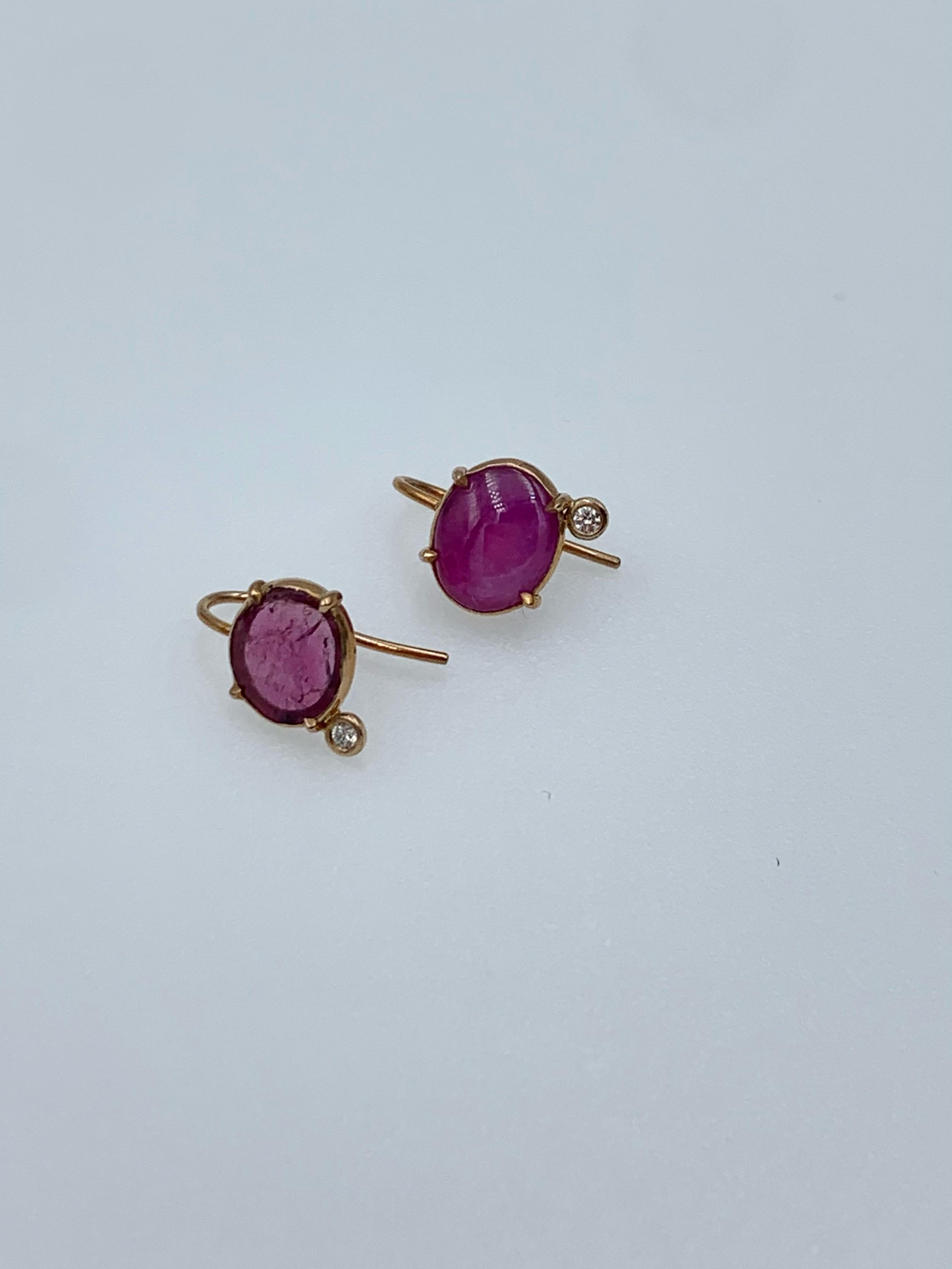These unique earrings are hand made from 9 karat rose gold, one has a rose cut Ruby slice and the other is a Ruby cabochon, both with a small 2 point diamond (or .02 carats) to one side. They are set to hang delicately off the ear with a shepherds