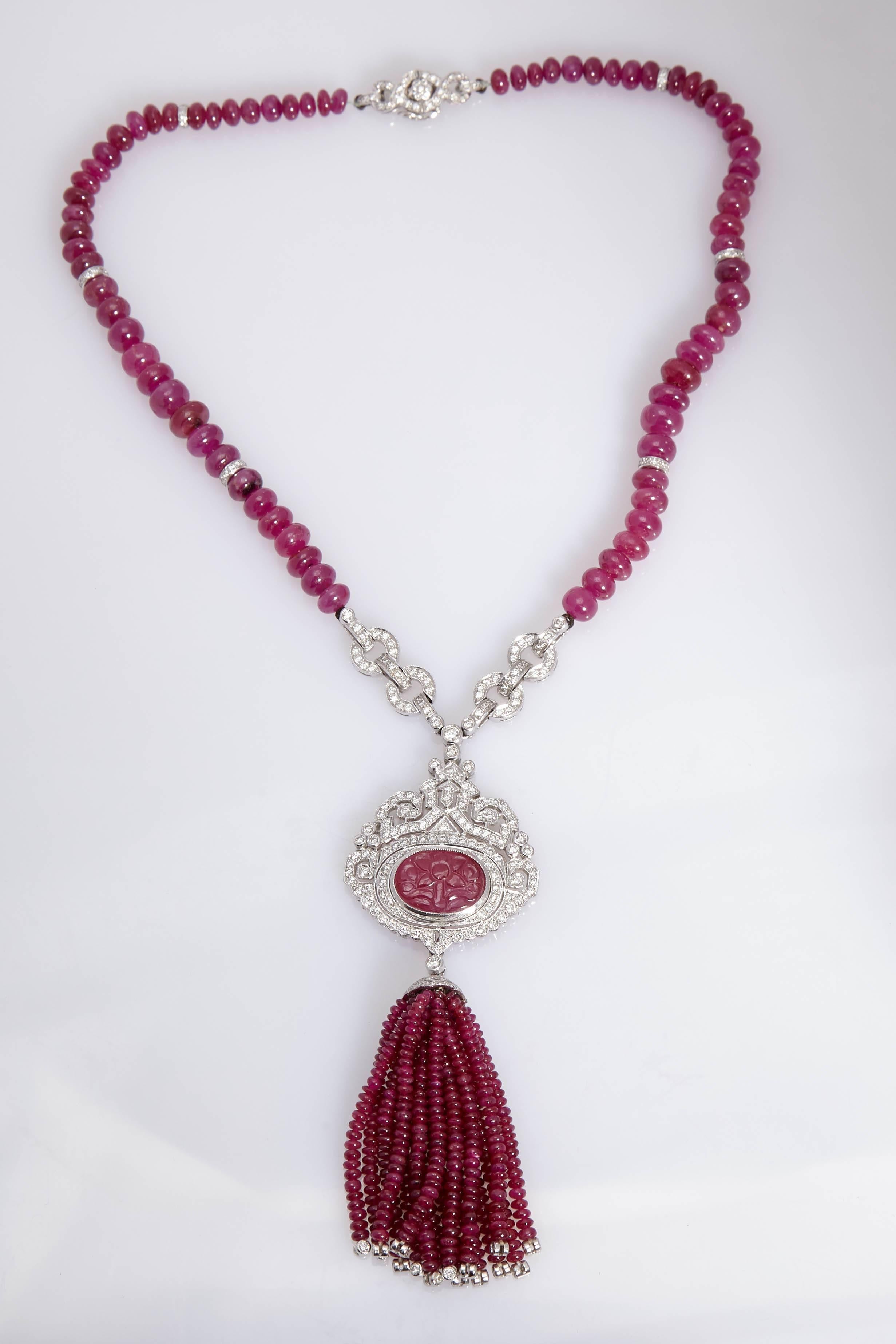 A beautiful sautoir drop necklace with natural (no heat) ruby beads, suspending a diamonds and carved ruby centre-piece of oriental design, with dangling smaller ruby beads tassel. Mounted on 18kt white gold, circa 1990s.