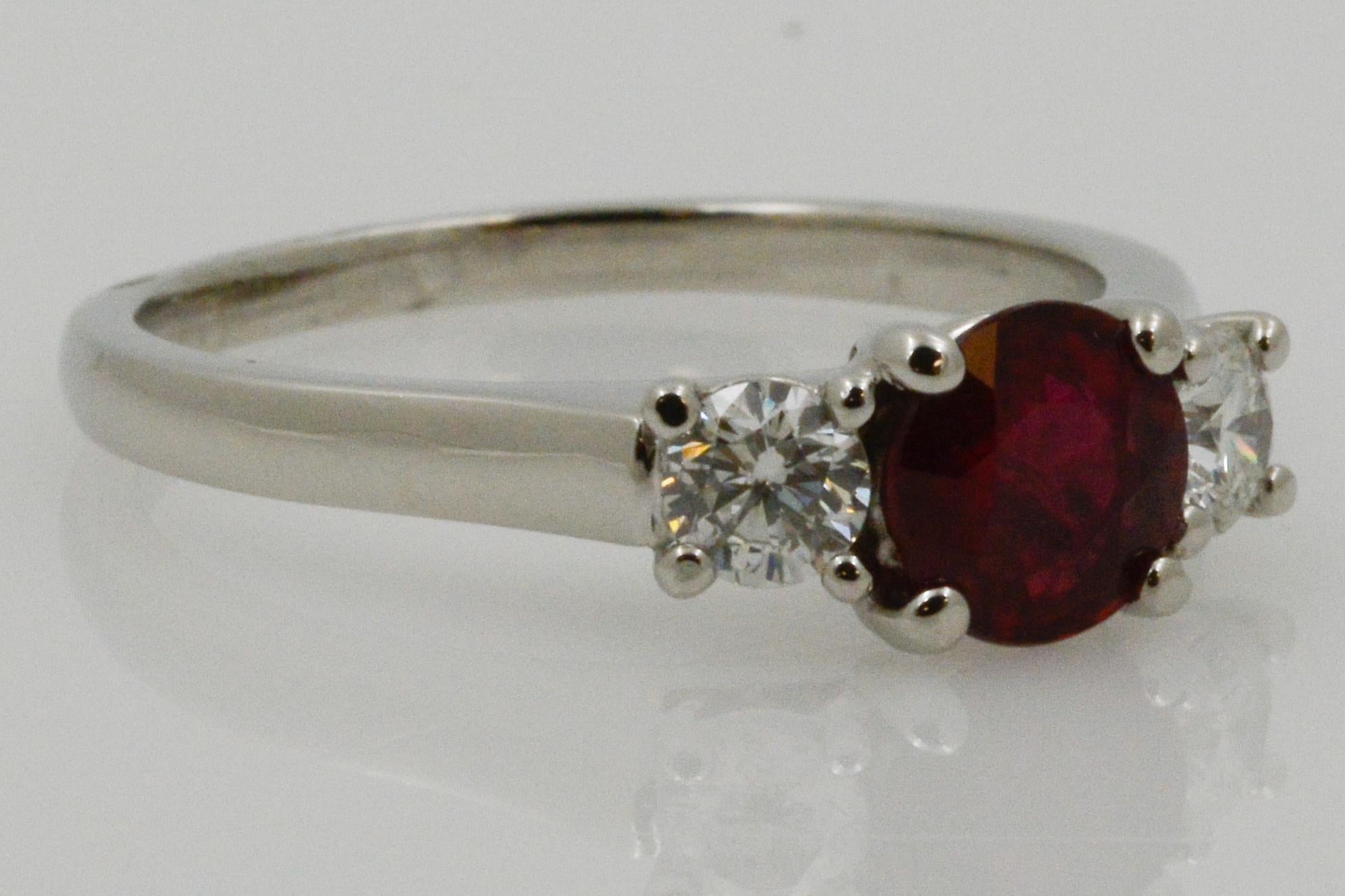 From Eiseman Jewels, this platinum three stone ring features a center round ruby 1.23ctw and is paired with two round brilliant cut diamonds .50ctw with H coloring and VS2 clarity. Size 8.25. 