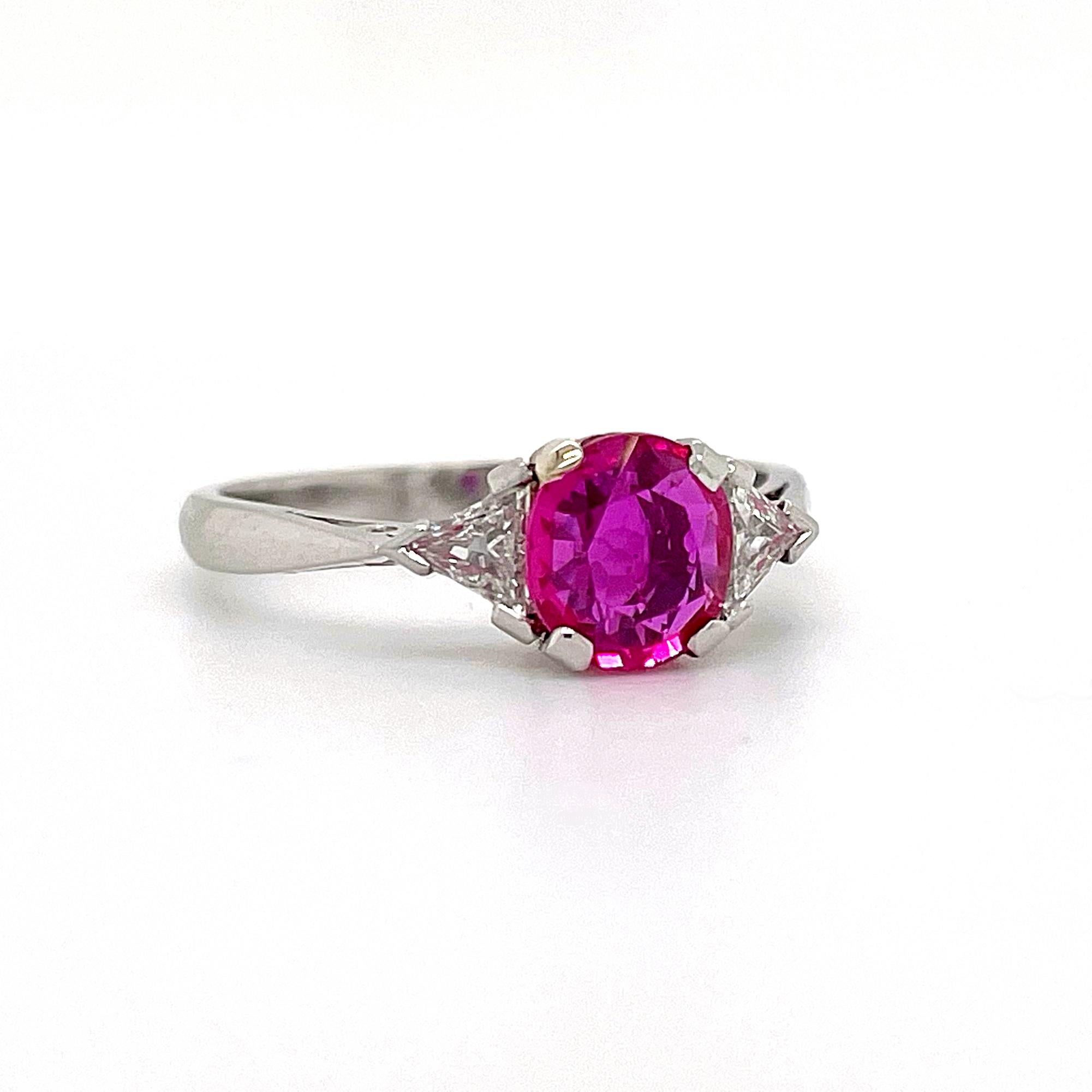 A stunning ruby and diamond ring in platinum. The round shaped ruby has a very bright pinkish colour, vivid crystal and is a very clean gemstone. It weighs approximately 1.2 carats and is probably of Burmese origin. The centre stone is harmoniously