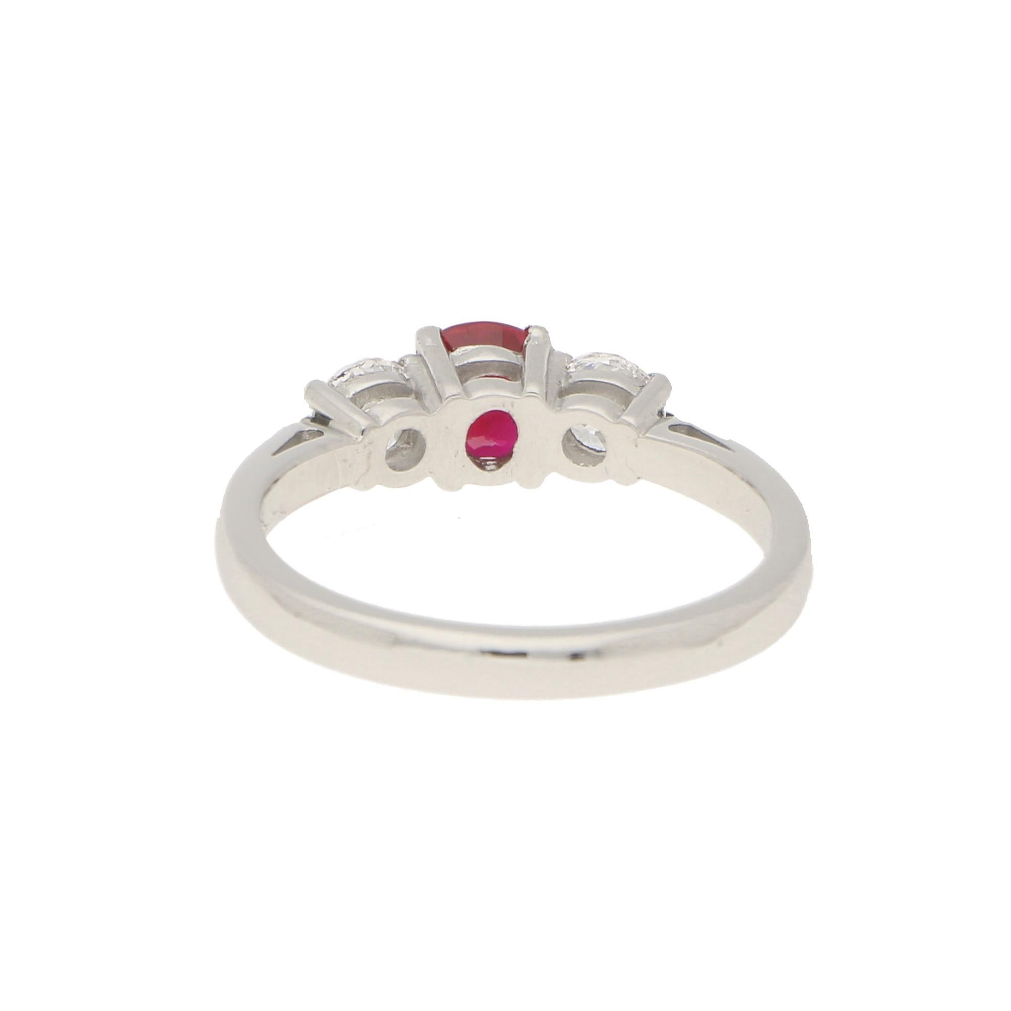 A beautiful ruby and diamond trilogy engagement ring set in 18k white gold. This classic design is centrally set with a cushion cut ruby four claw set in an open back triple setting. The vibrant red ruby is then flanked to each side by two sparkly