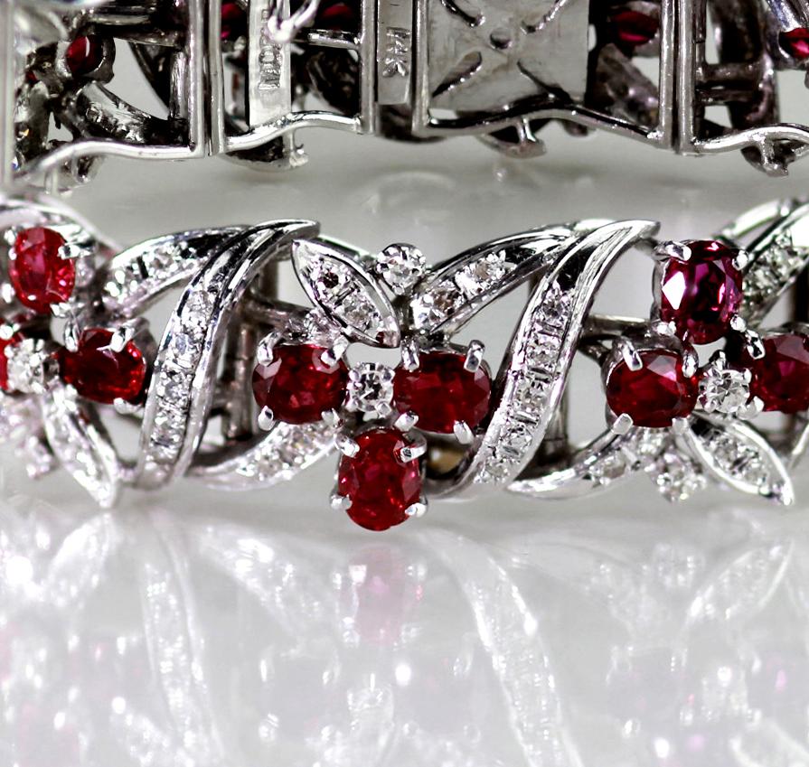A gorgeous 18kt white gold, ruby and diamond bracelet, designed to resemble floral clusters entwined within sparkling ribbons of diamonds. The bangle has a hinged clip fastening with safety clip for added security and is composed of 42 oval faceted