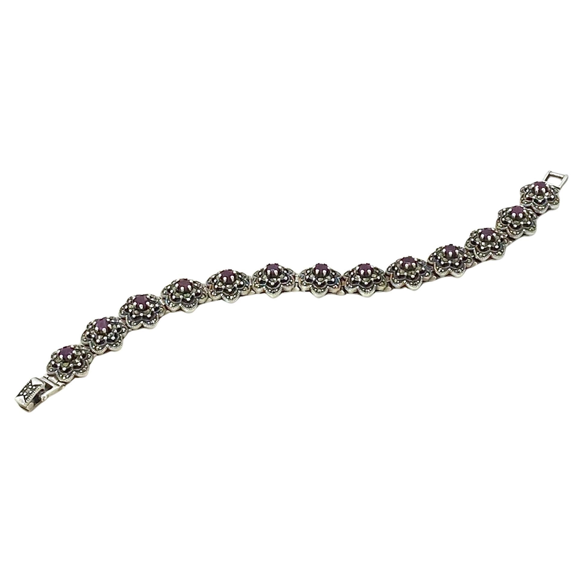 This is a ruby and marcasite sterling link bracelet. This hinge bracelet links with 13 prong set ruby and marcasite flower shaped segments with a fold over clasp. Marked .925 on the clasp.

Our vintage jewelry collection and original creations are