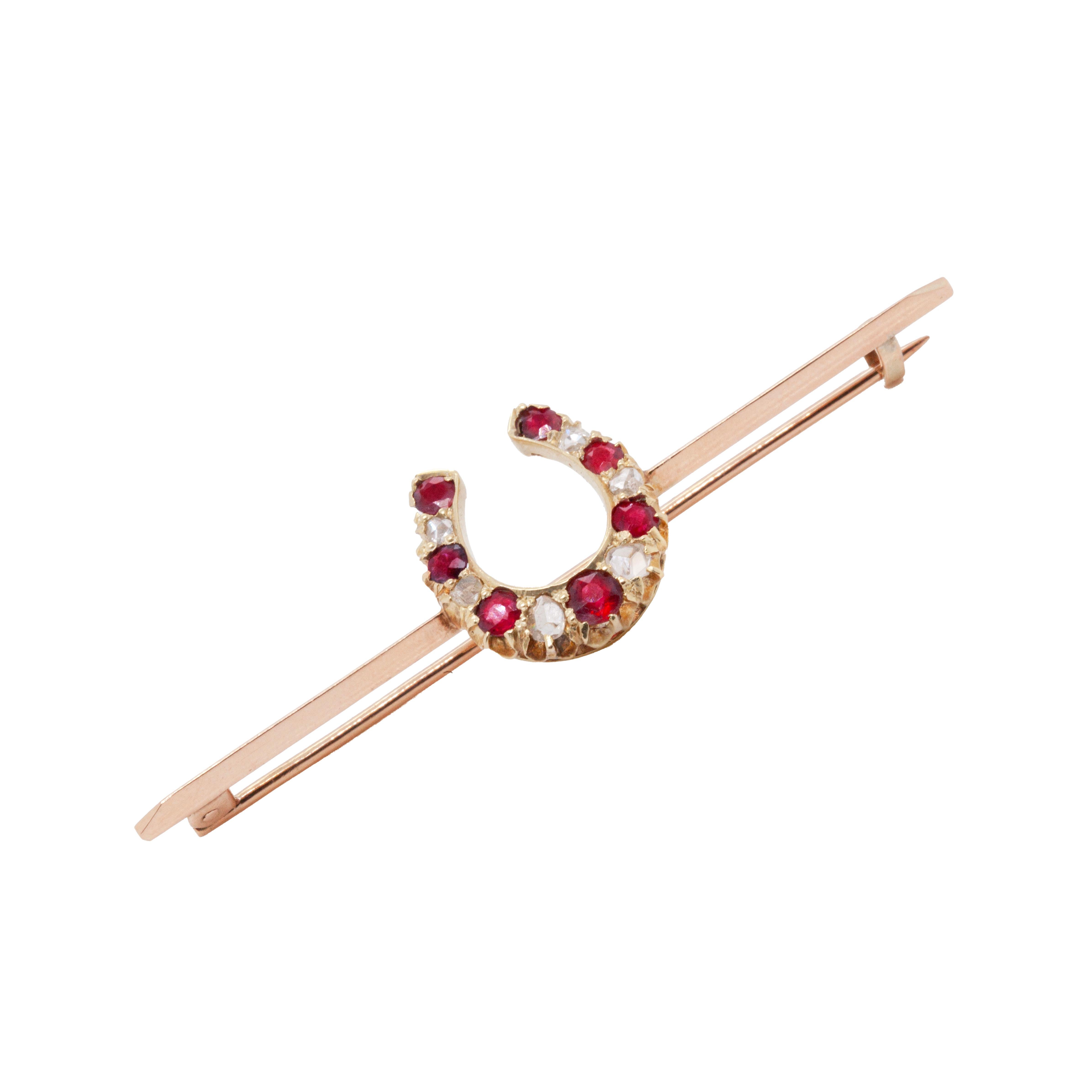 Introducing an elegant antique bar brooch from the 1920's, showcasing a delicate, lucky horseshoe at the centre.

Decorating the horseshoe there are 7 lively red rubies with an approximate combined weight of 0.50ct, beautifully alternating with 6