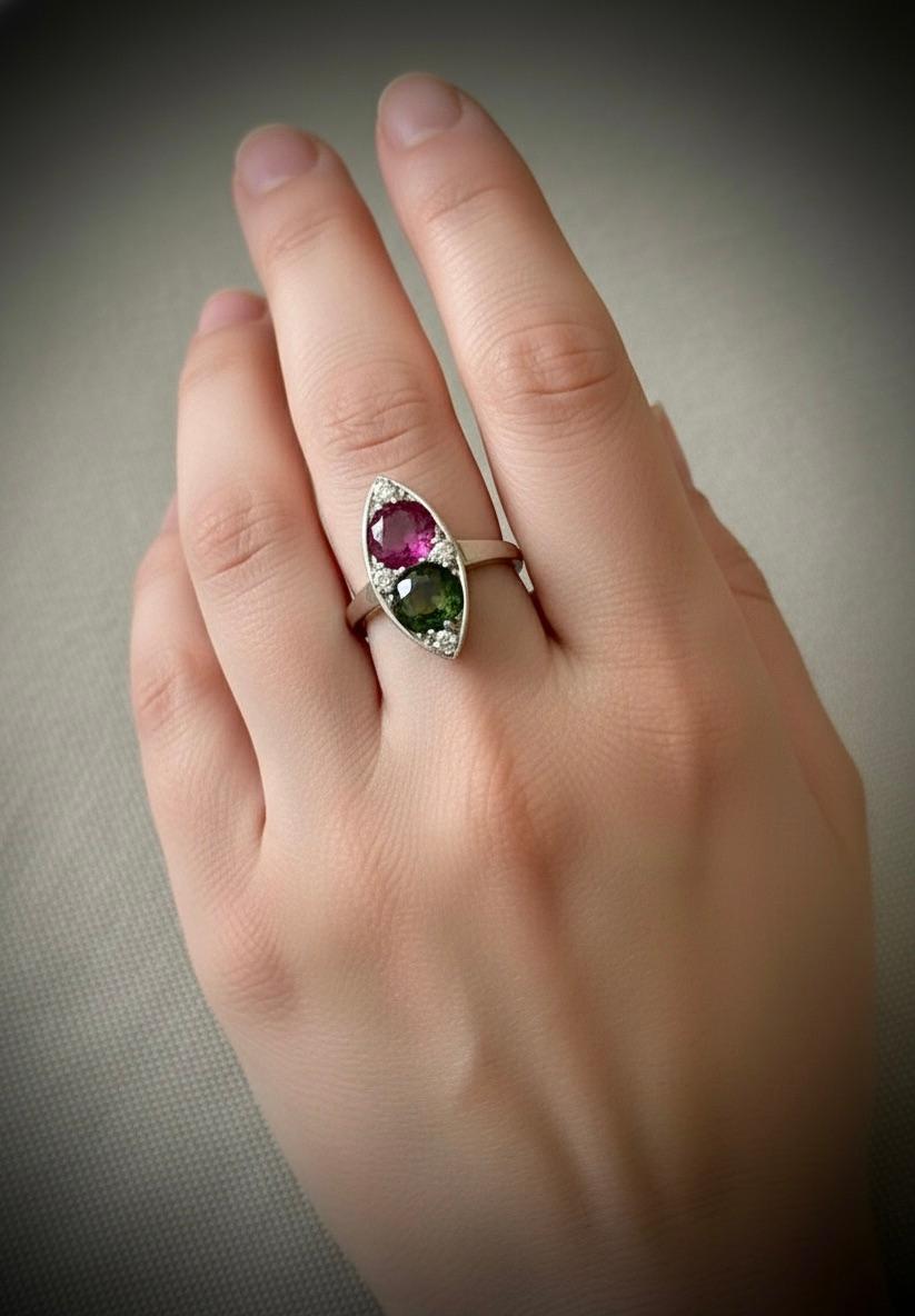 Un antico anello in stile Art Deco con rubino naturale e zaffiro in platino.  L'anello è impreziosito da un rubino rosa antico rotondo non trattato, da uno zaffiro blu-verde e giallo a taglio rotondo e da quattro diamanti bianchi rotondi a taglio