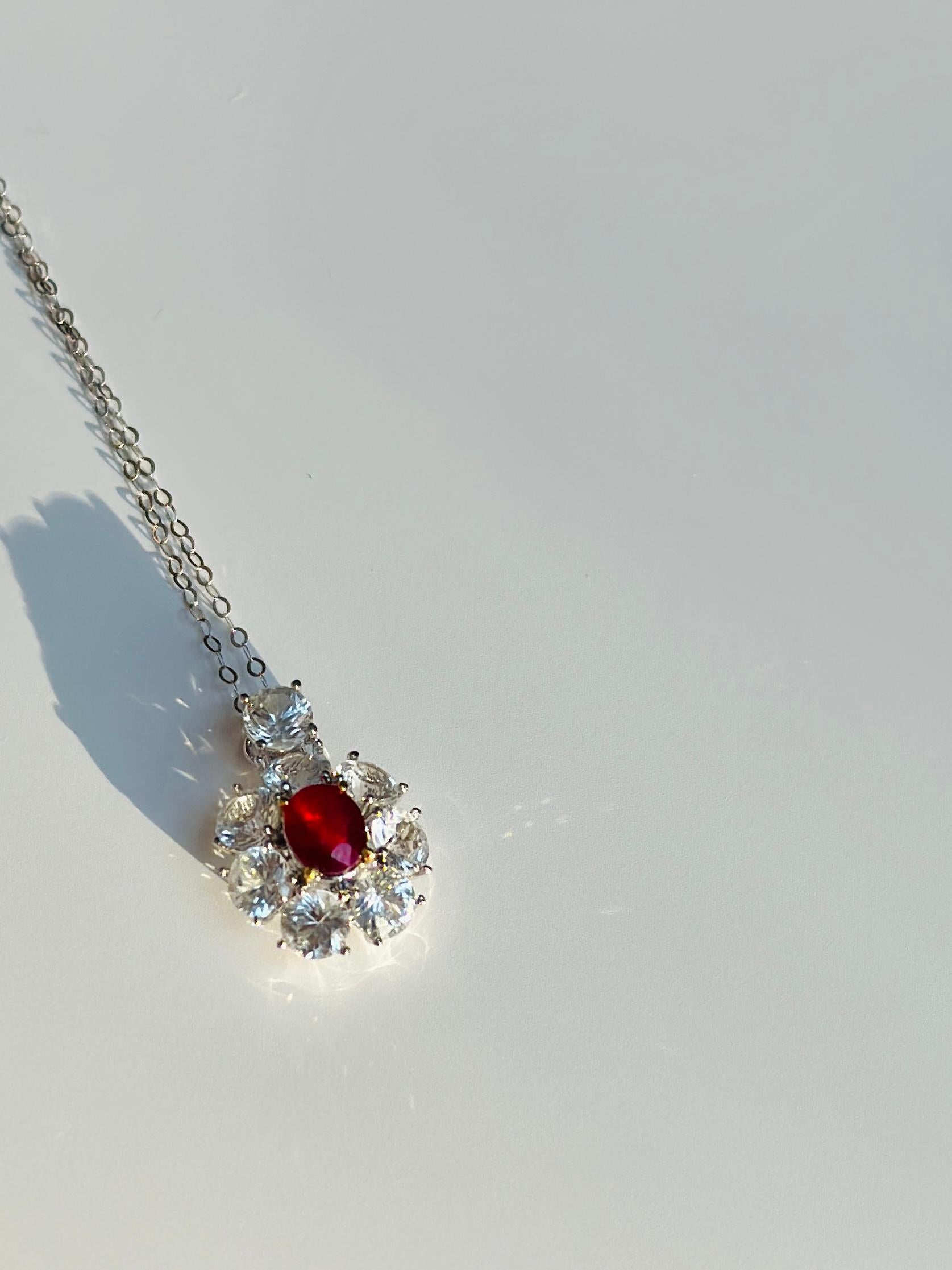 This gorgeous piece of jewelry features a stunning ruby and white sapphire pendant set in 18-karat gold. The pendant showcases a radiant ruby in the center, surrounded by shimmering white sapphires, creating a captivating contrast of colors. The