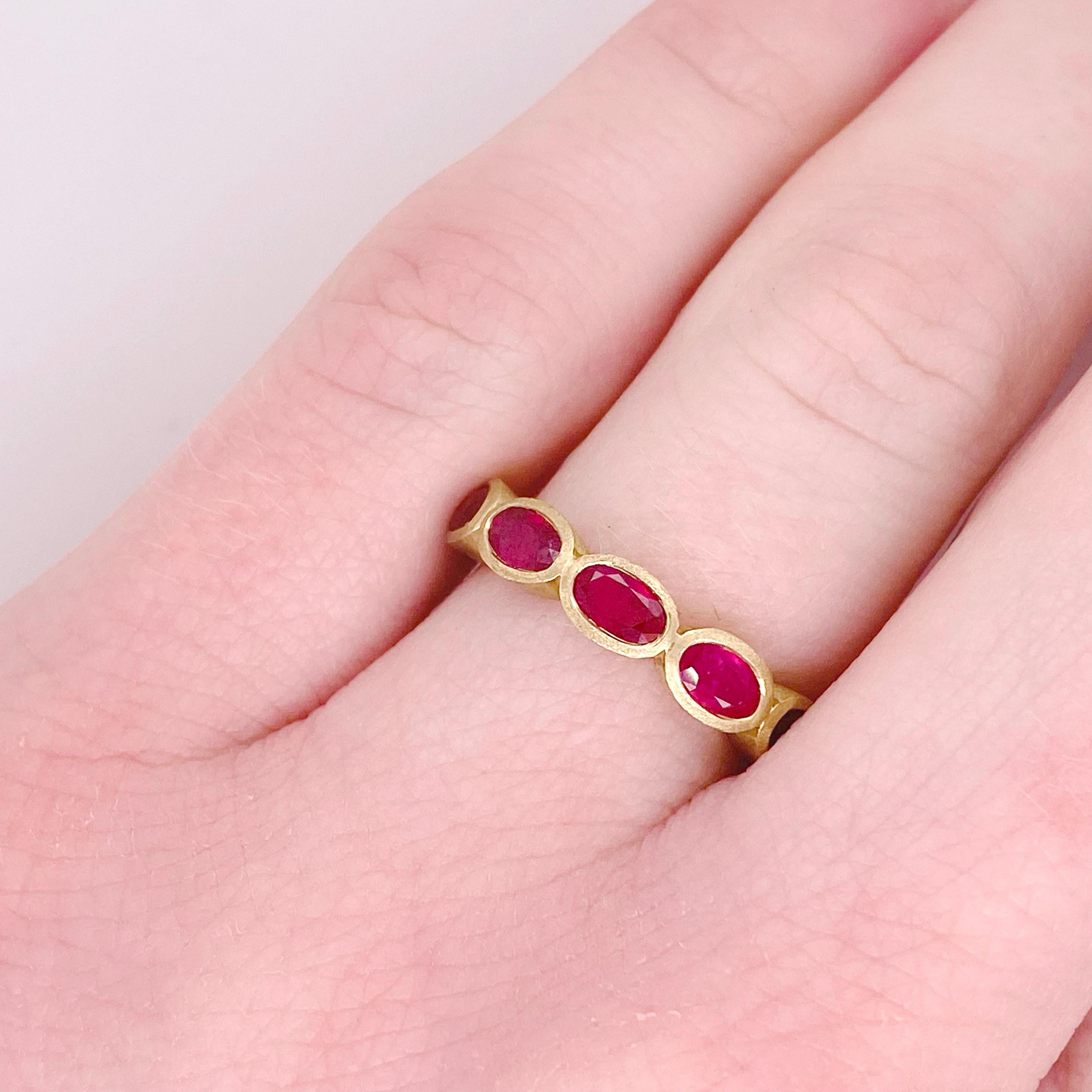 This 14 karat handmade ruby ring has five oval rubies set east to west. This dynamic design is gorgeous going across any finger. The five rubies have a total weight of 1.52 carats. The satin gold looks perfect when paired with high-polished rings.