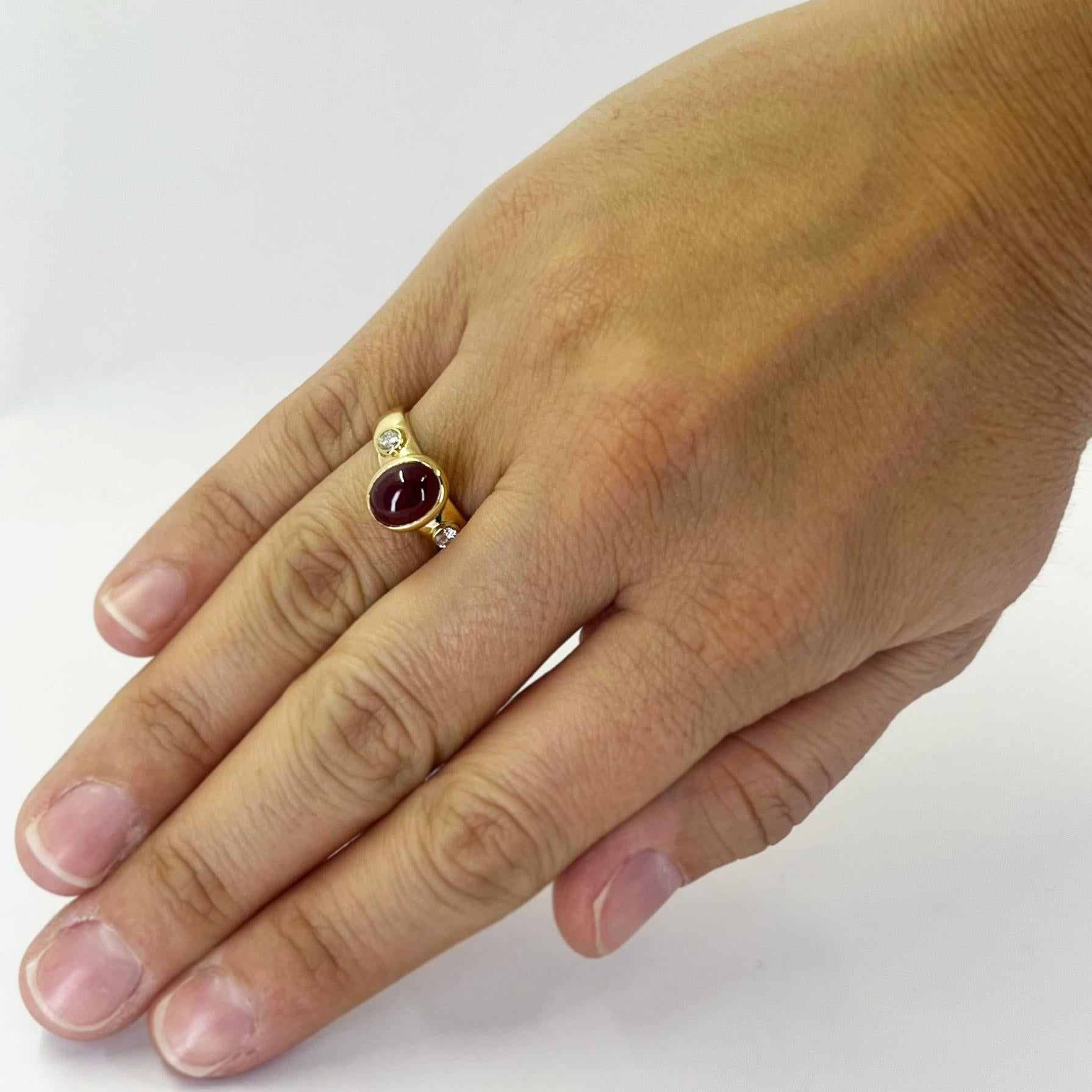 Bague en or jaune 18 carats ornée d'un rubis cabochon ovale d'un poids estimé à 1,00 carat et de deux diamants ronds de pureté VS et de couleur H totalisant environ 0,20 carat. Taille des doigts 6.5. Le poids fini est de 6,3 grammes.

Également