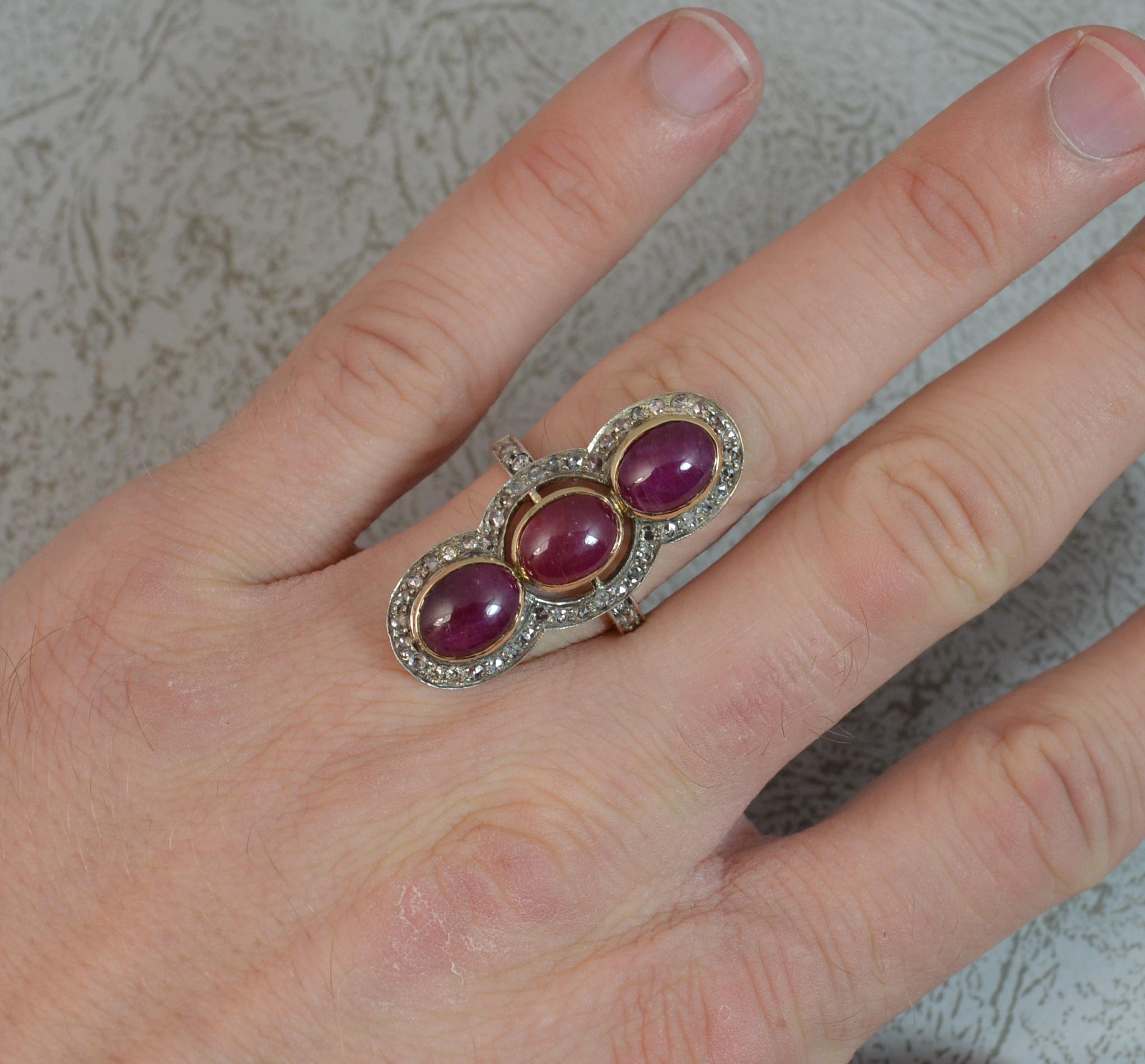 A fantastic vintage cluster or panel ring.
Solid 14 carat gold example.
Large three cluster panel type design.
13mm x 33mm cluster head. Designed with three large oval cabochon ruby stones with a halo of smaller rose cut diamonds surrounding and