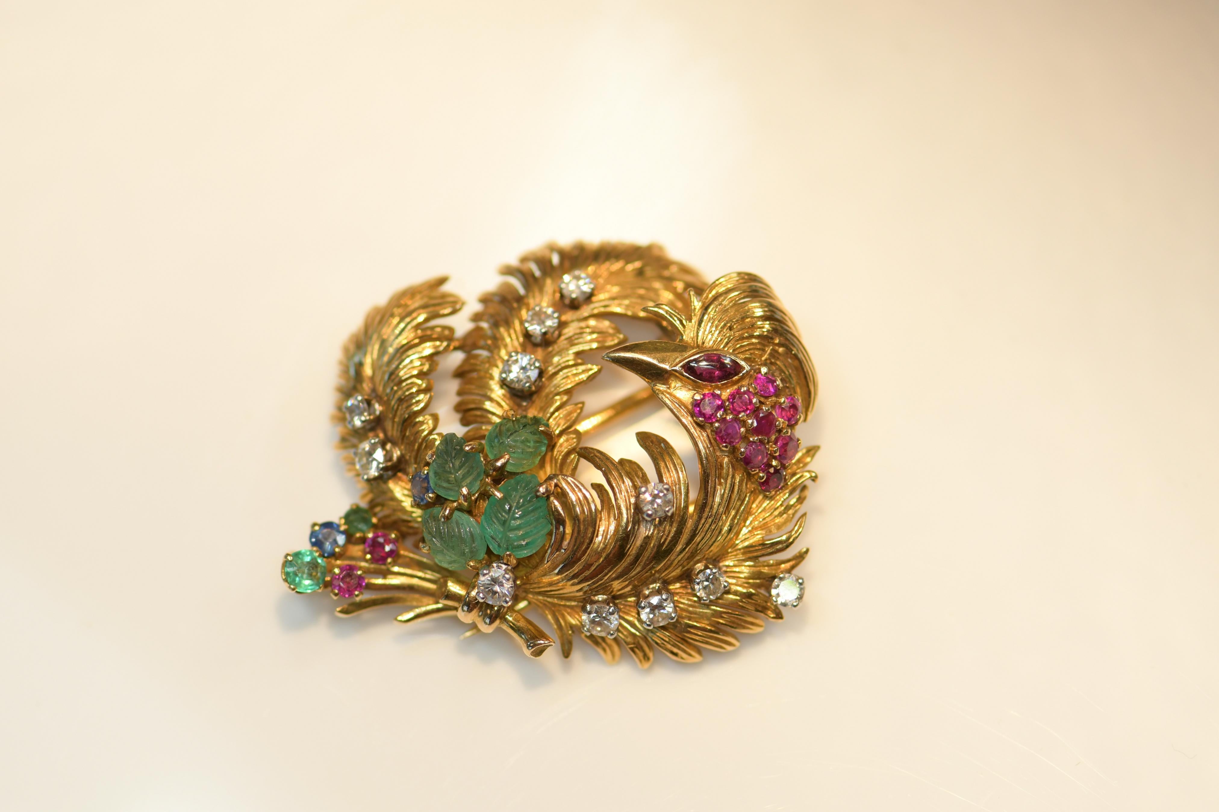 This is a beautifully designed phoenix brooch. The colour combination of ruby, diamond and carved emerald is reminiscent of the tutti frutti giving it a very distinctive style. The jeweller's skill to create this piece is shown by the attractive