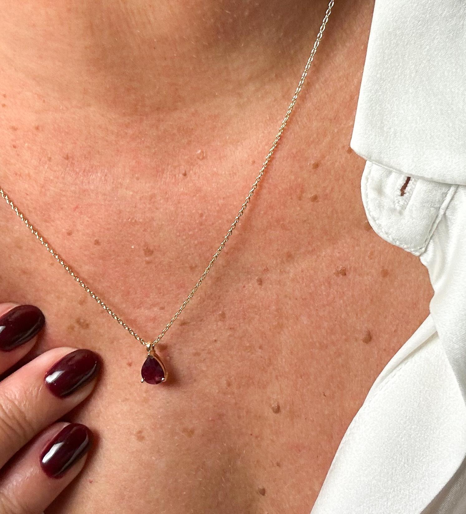 This pendant necklace in 18-carat yellow gold embodies elegance and sophistication at their finest. It is adorned with a natural, pear-cut certified by GIL pigeon's blood ruby that captures the essence of love and passion. The ruby, weighing 0.87