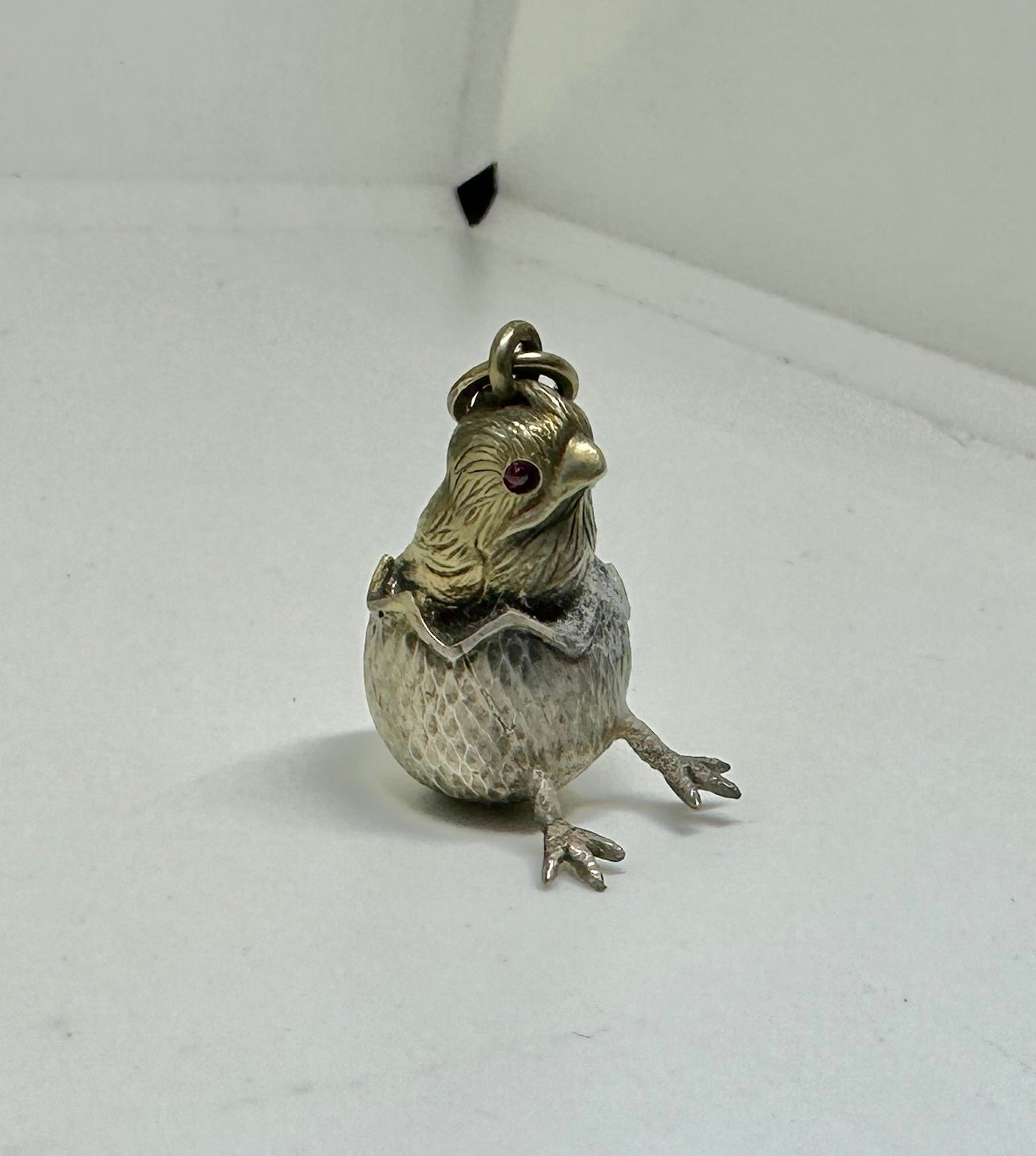 This is a wonderful antique Russian Chick in Easter Egg with Ruby Eyes pendant or charm in Silver.  The chick pendant is Hallmarked on the bale with the Faberge Workmaster mark of Albert Holmström – mark AH – active 1903-1917.  It is also marked